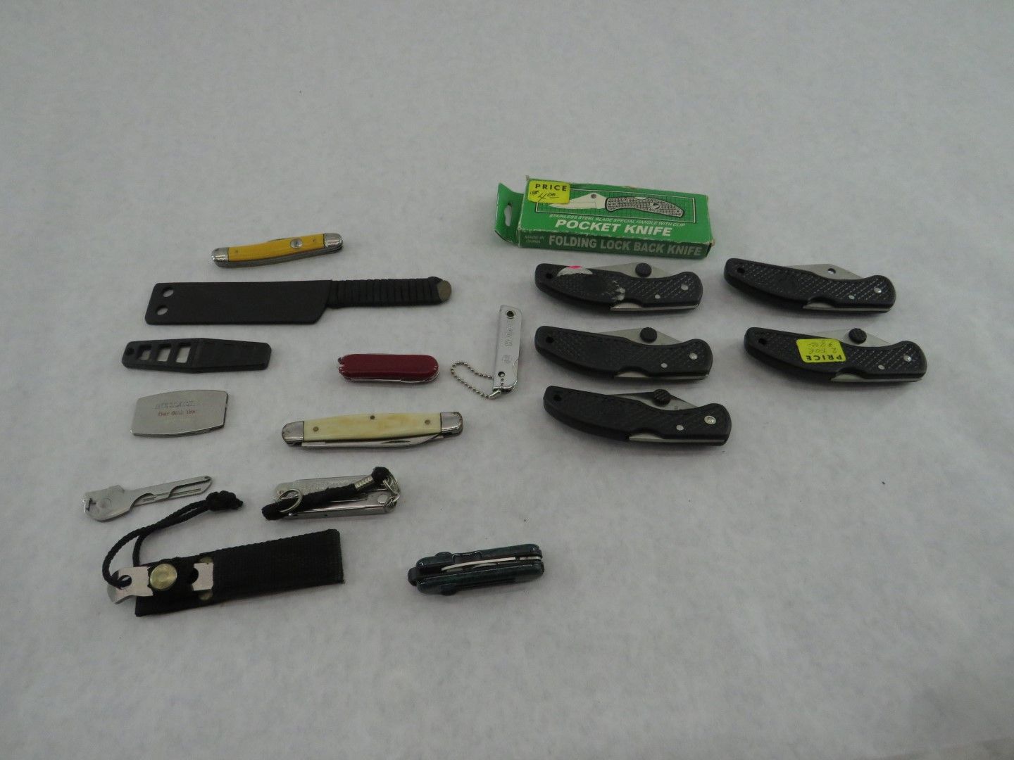 Collection of various pocket knives and blades on a white surface.