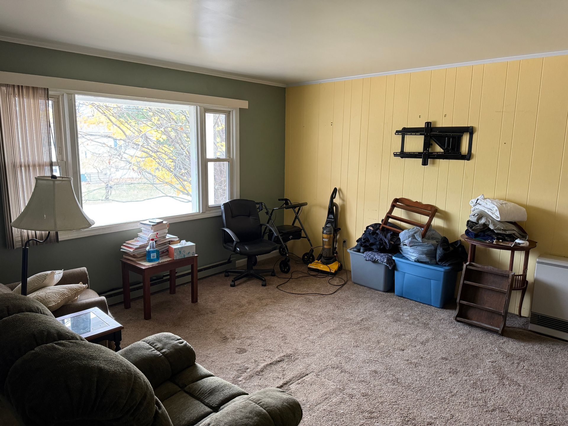 Living room with a sofa, window, office chair, and storage bins on the floor.