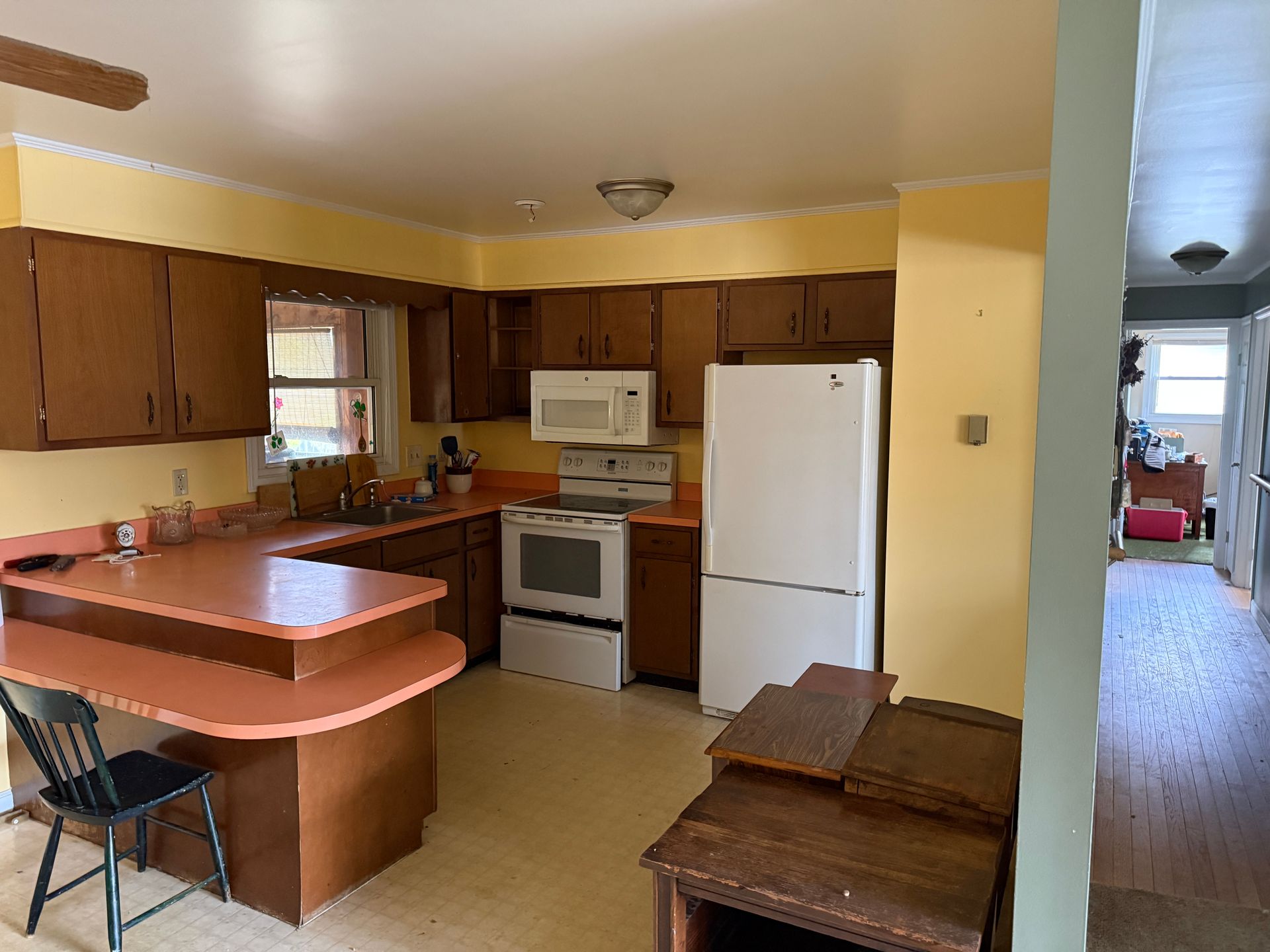 Kitchen with wood cabinets, orange countertops, white appliances, and a hallway.