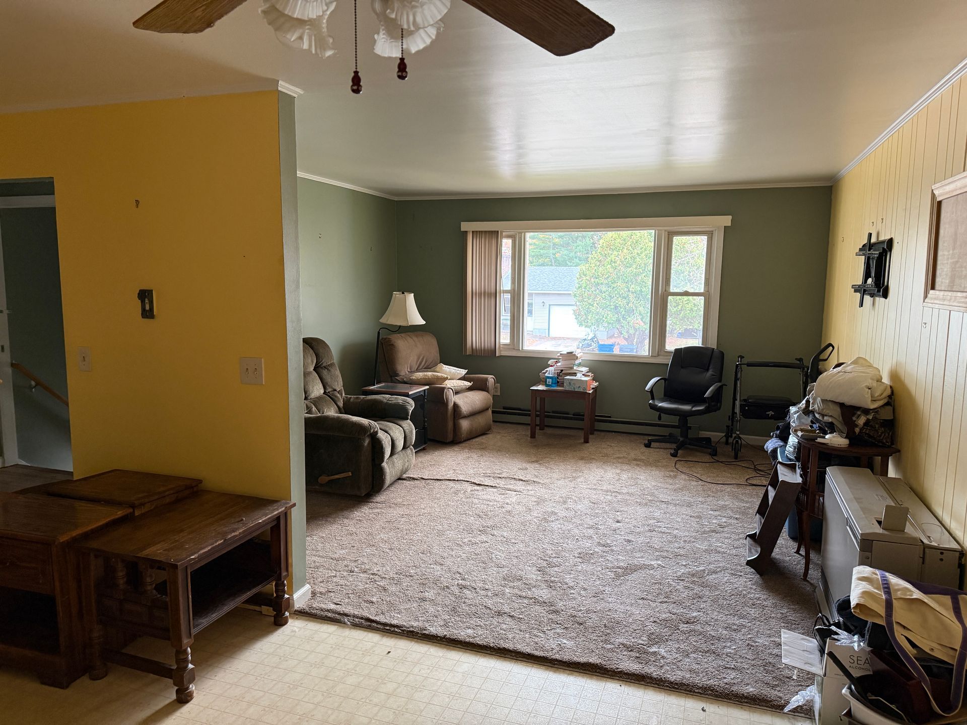 A living room with green and yellow walls, a brown recliner, a window, and a tan rug.