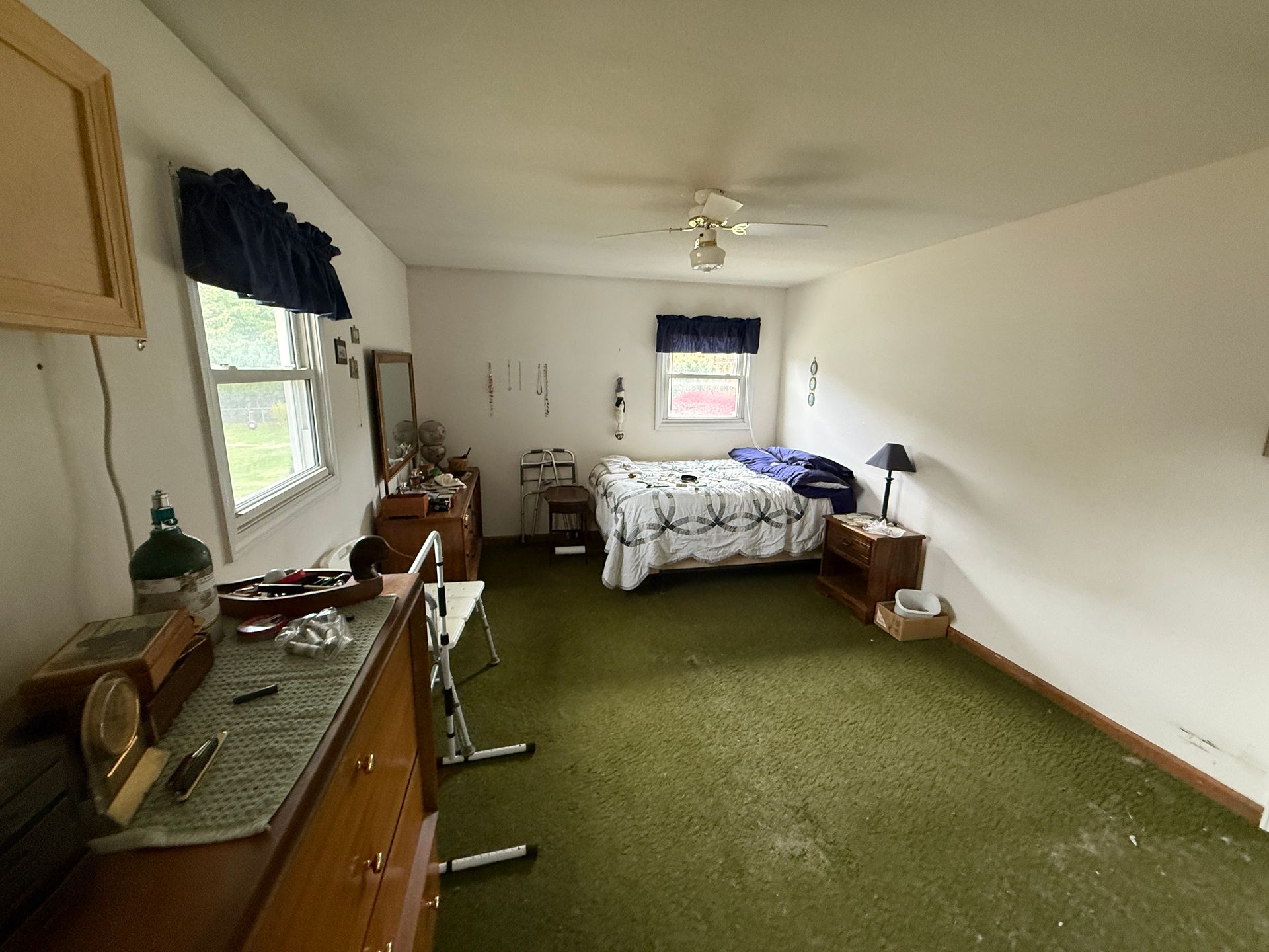 Bedroom with green carpet, white walls, bed, dresser, and a window.