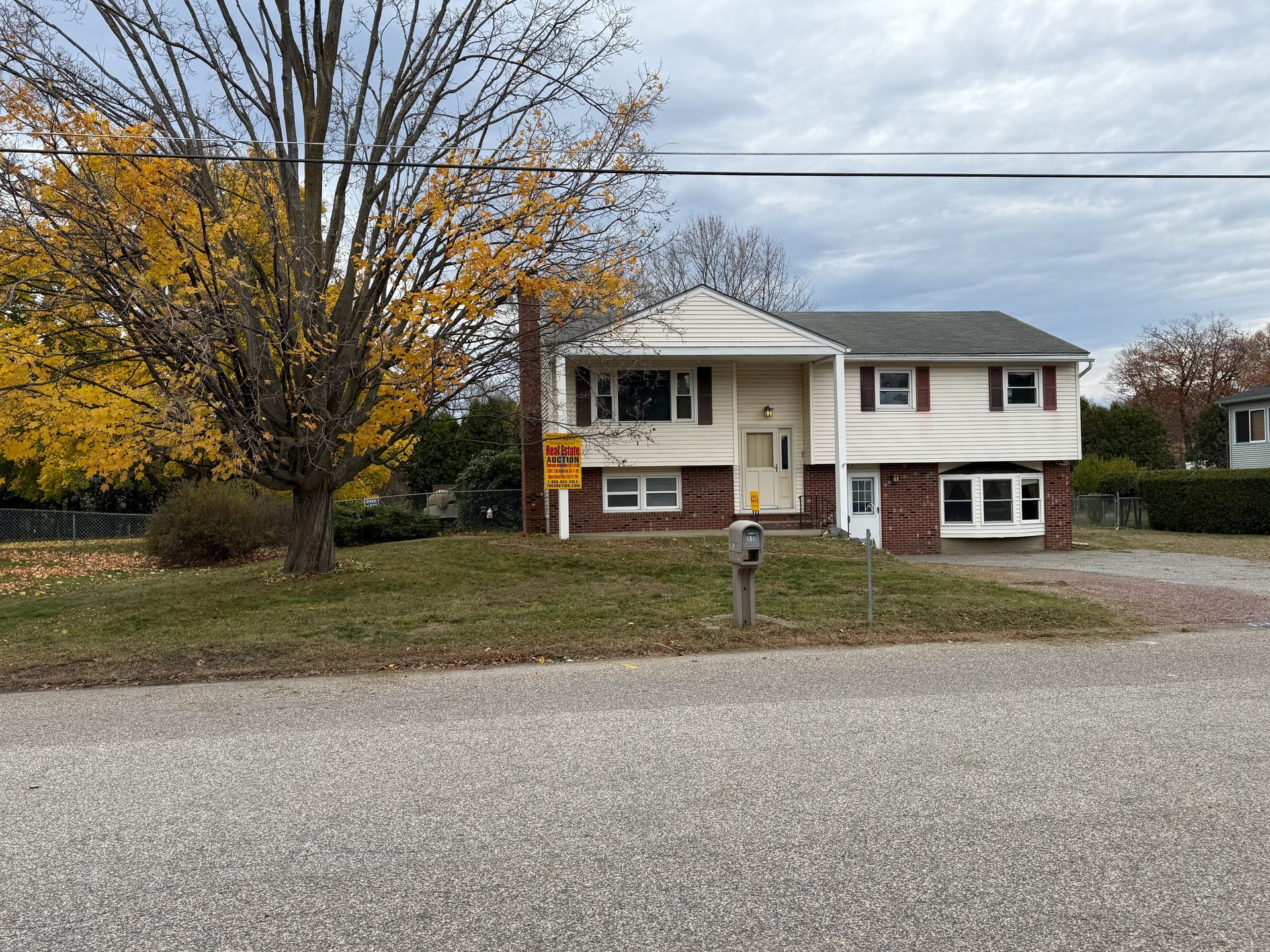 House for sale, split-level style with brick and white siding. Autumn trees in the yard.