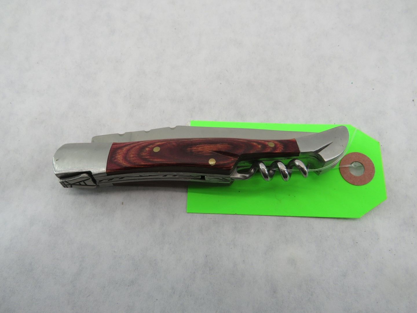 Wine opener with a wooden handle and corkscrew, on a green tag.