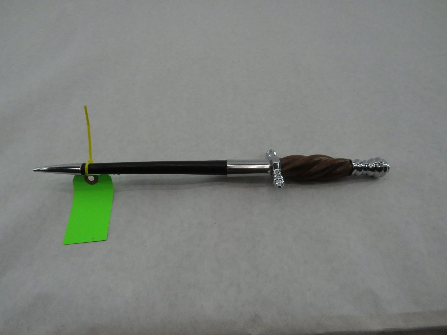 A dagger-shaped pen with a wooden handle and silver accents. It has a long, pointed tip.
