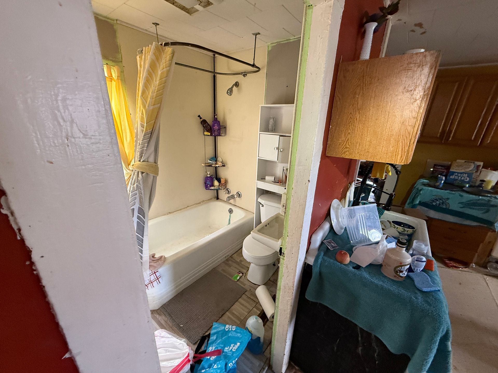 Bathroom with bathtub, toilet, and shelving.
