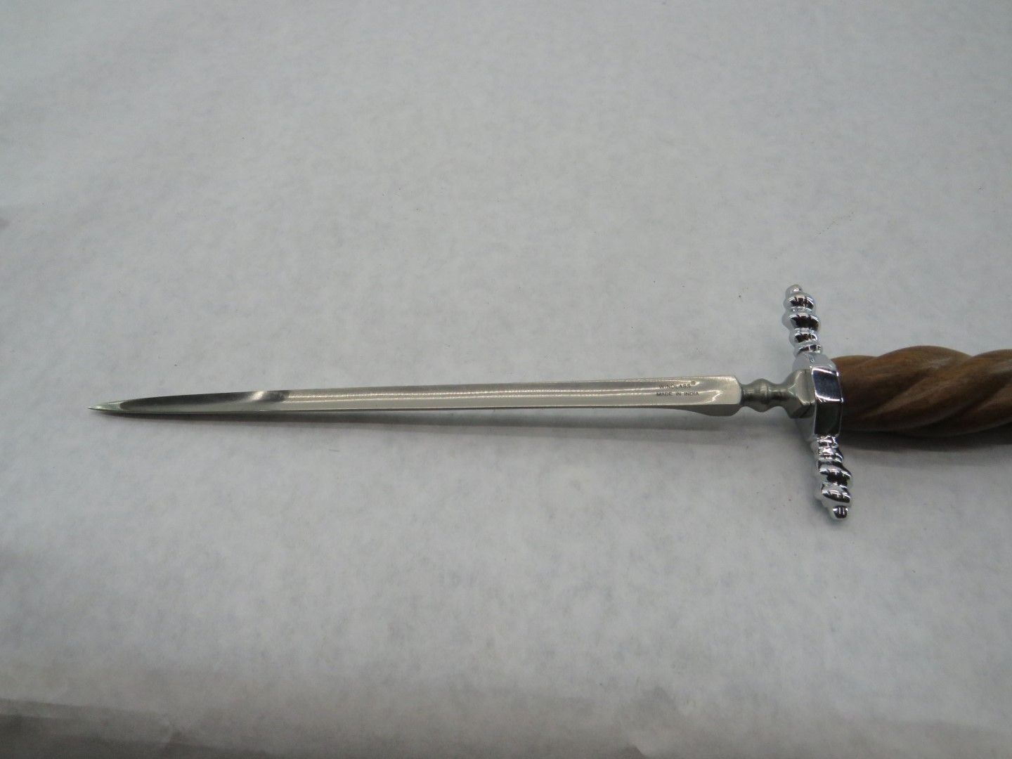 Silver dagger with crossguard and wooden handle, on a white surface.
