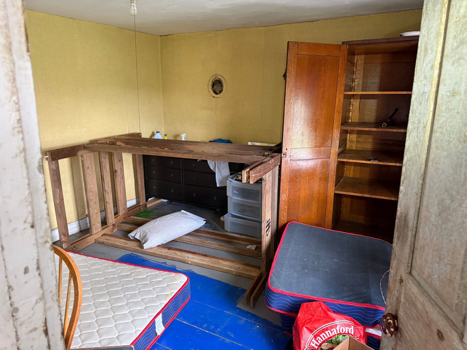 Room with makeshift platform bed. Yellow walls, wooden furniture.