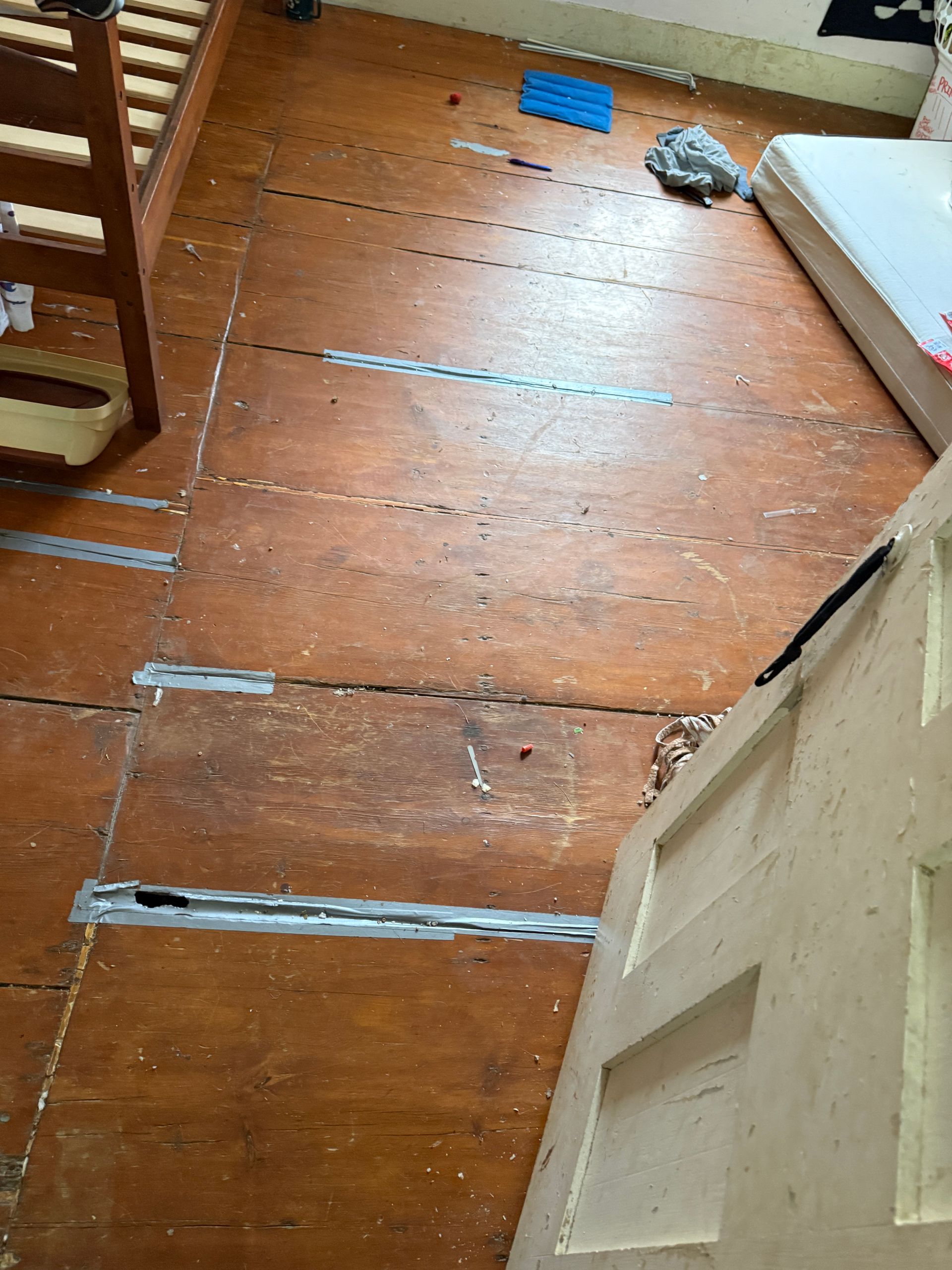 Wooden floor with bed frame visible.