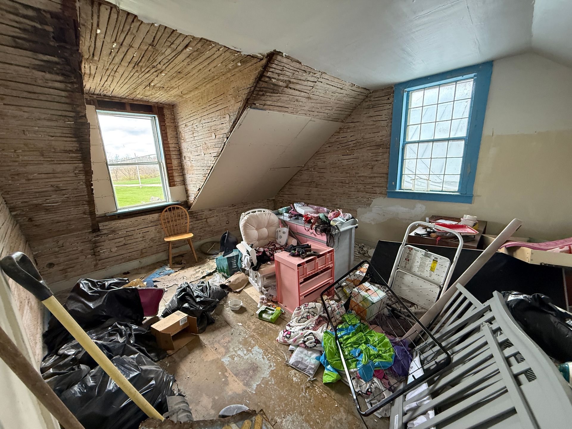 Attic room with two windows, and exposed brick and plaster walls.