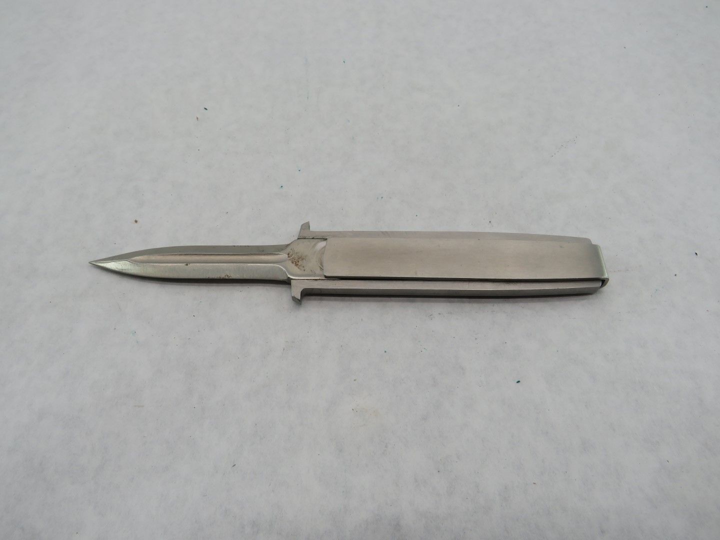 Silver dagger with pointed blade, extended from a rectangular handle.