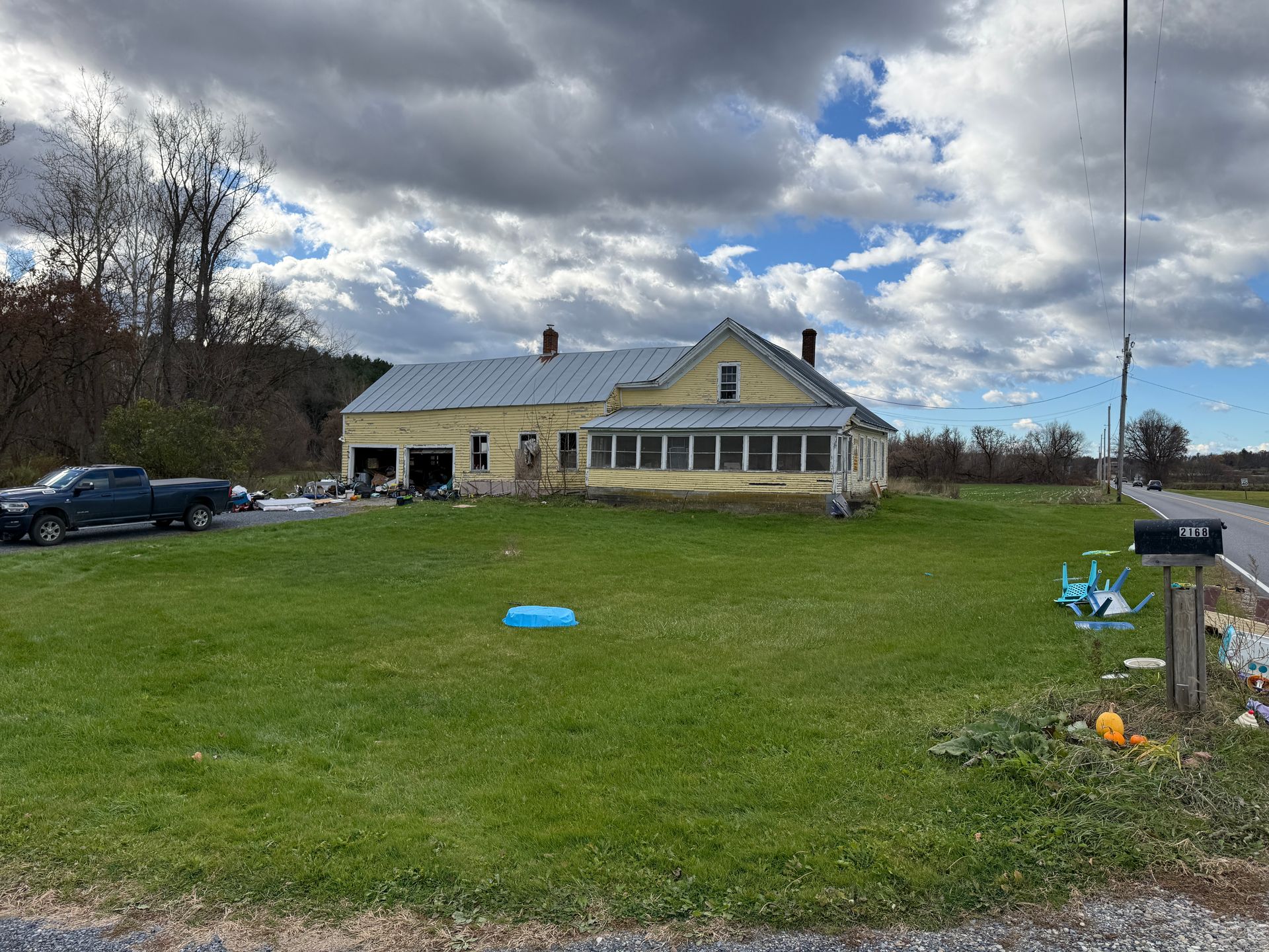 Yellow house on a grassy lot, under a cloudy sky.
