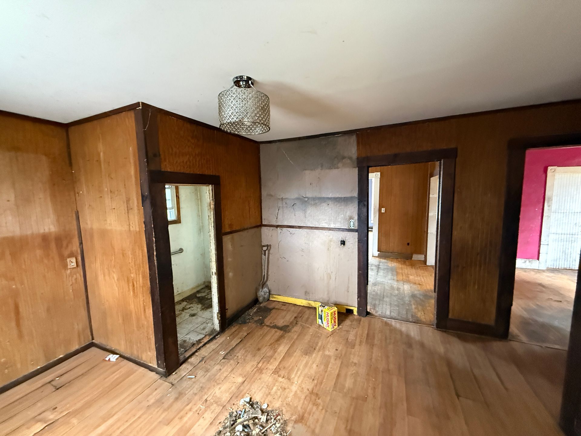 Interior room undergoing renovation with wood paneling, open doorways.