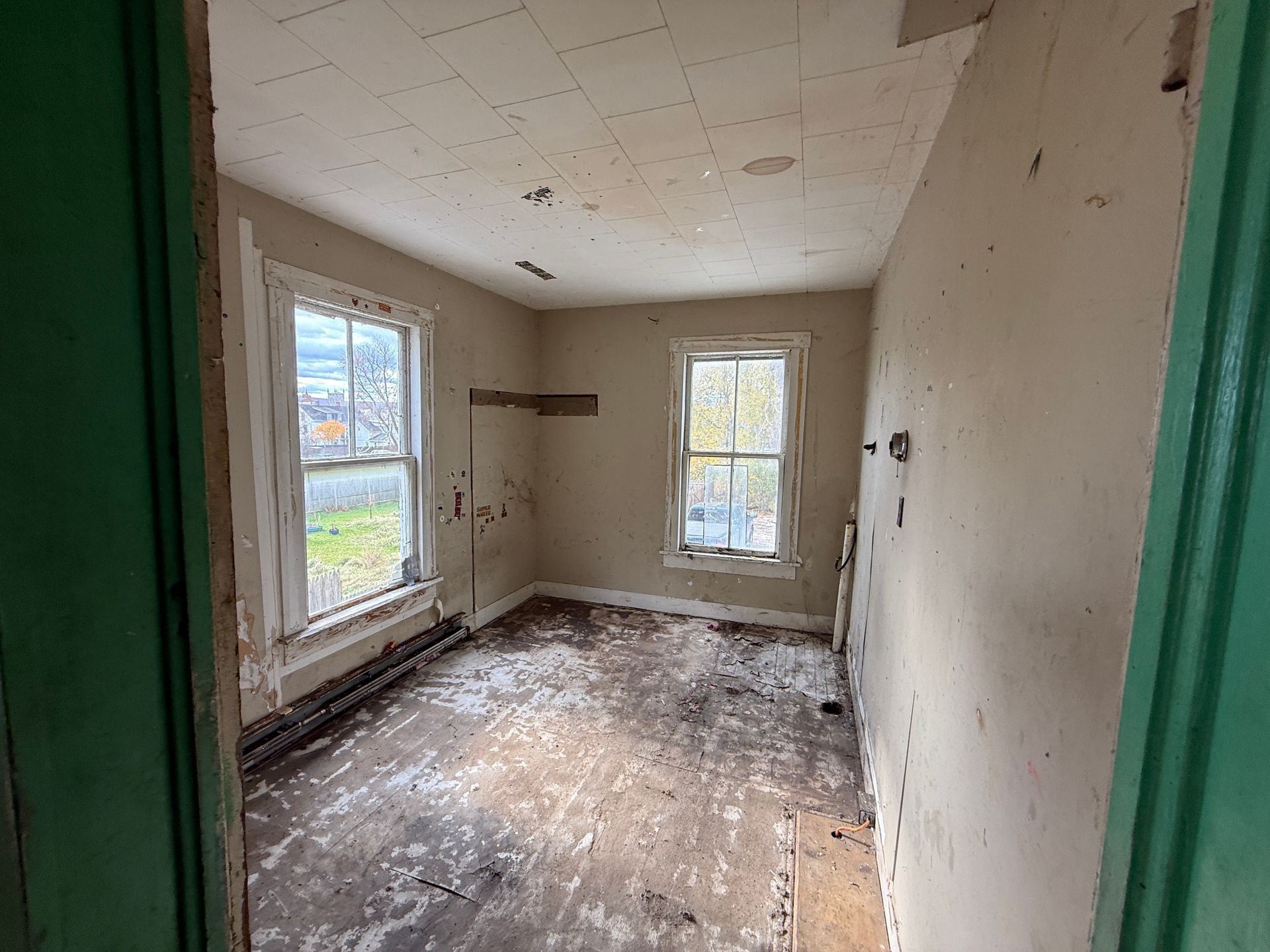 Interior of a room with two windows, paint, and floorboards.