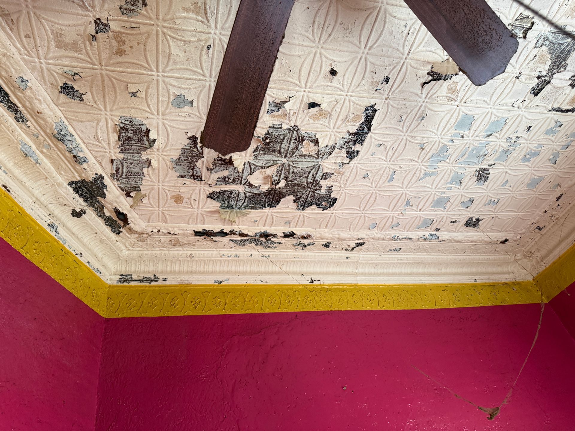 Textured ceiling with paint, brown ceiling fan, yellow and red walls.