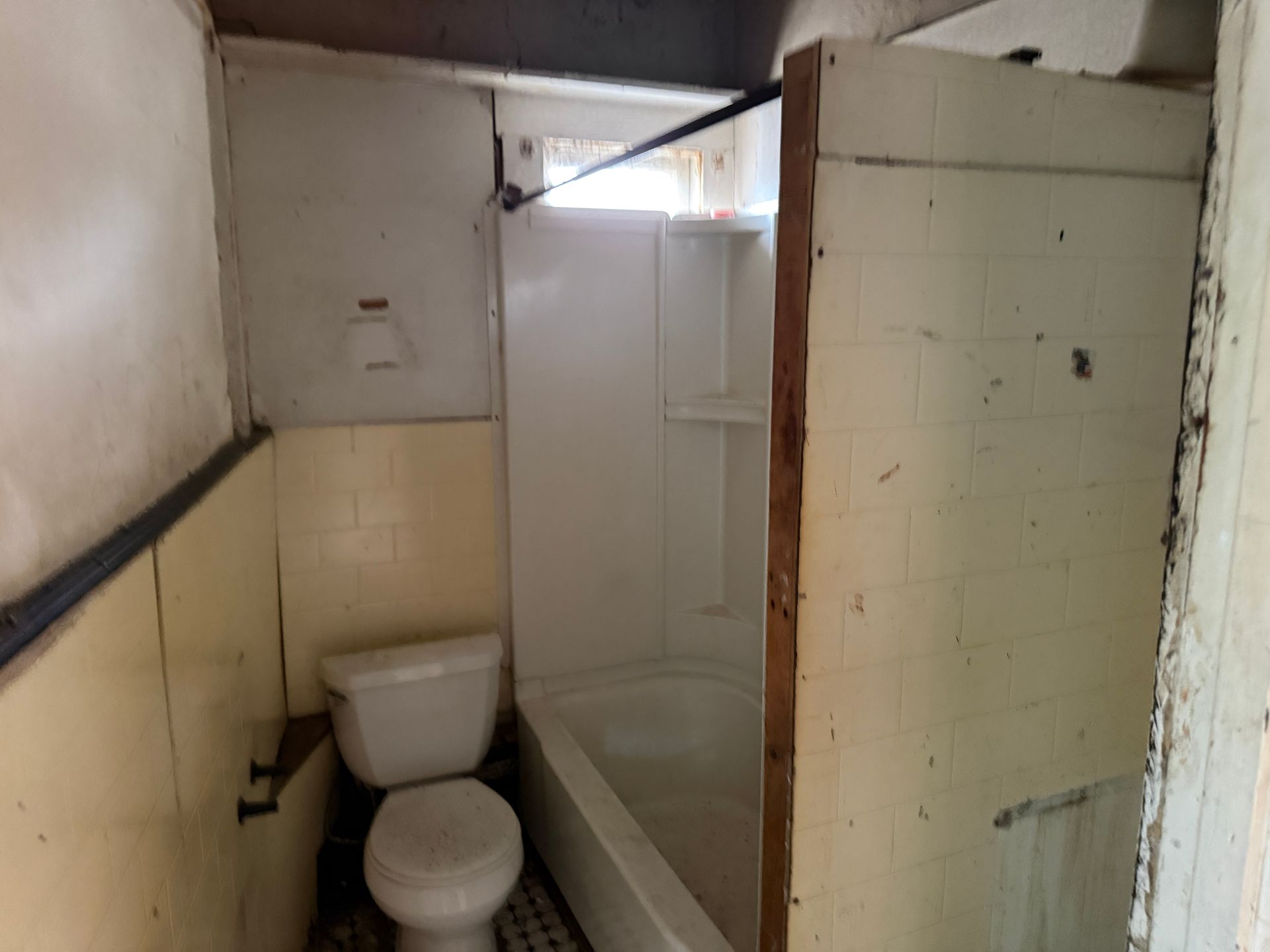 Small, bathroom with a toilet, bathtub, and walls.