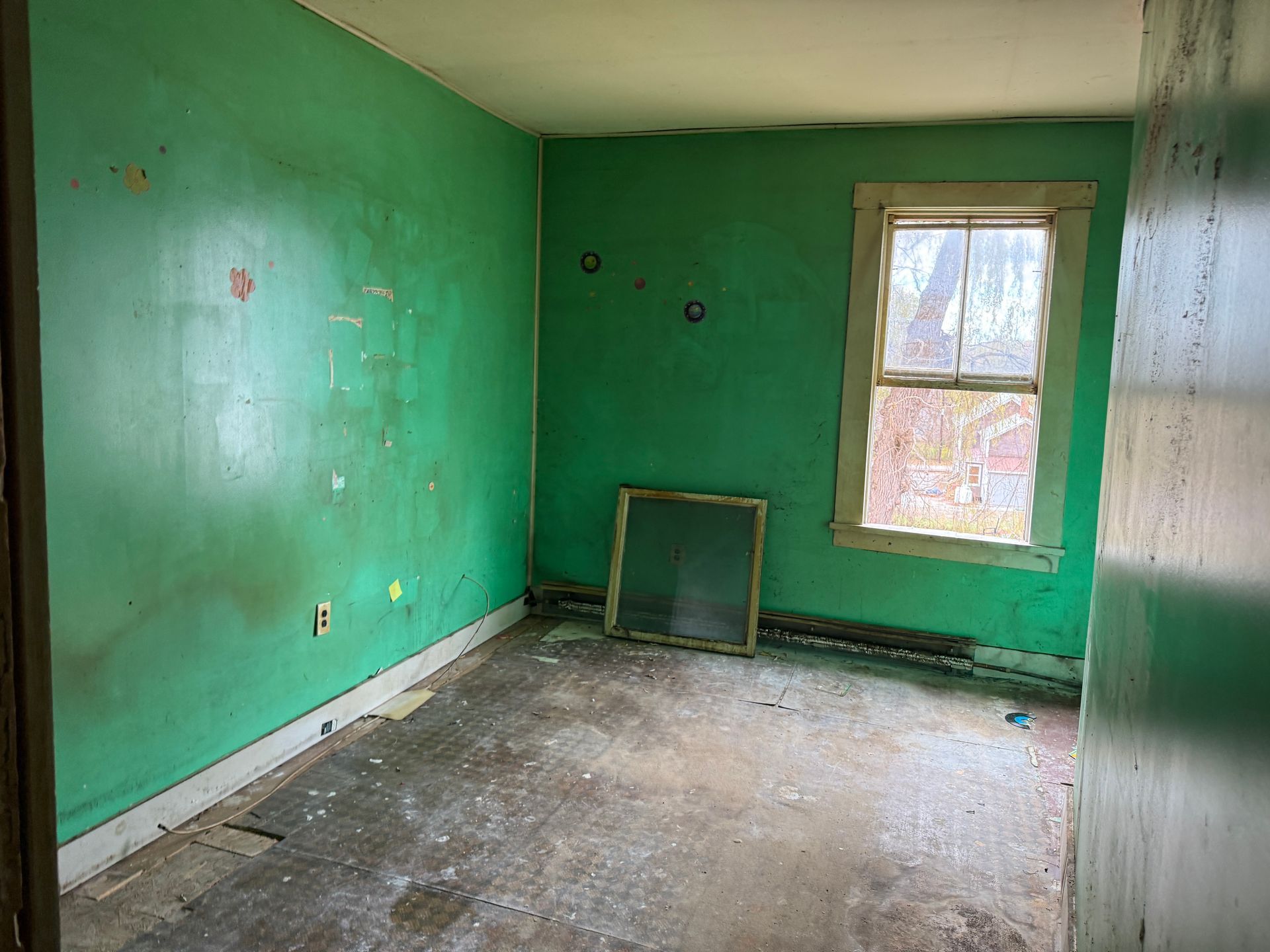 Empty room with green walls, a window, and floor.