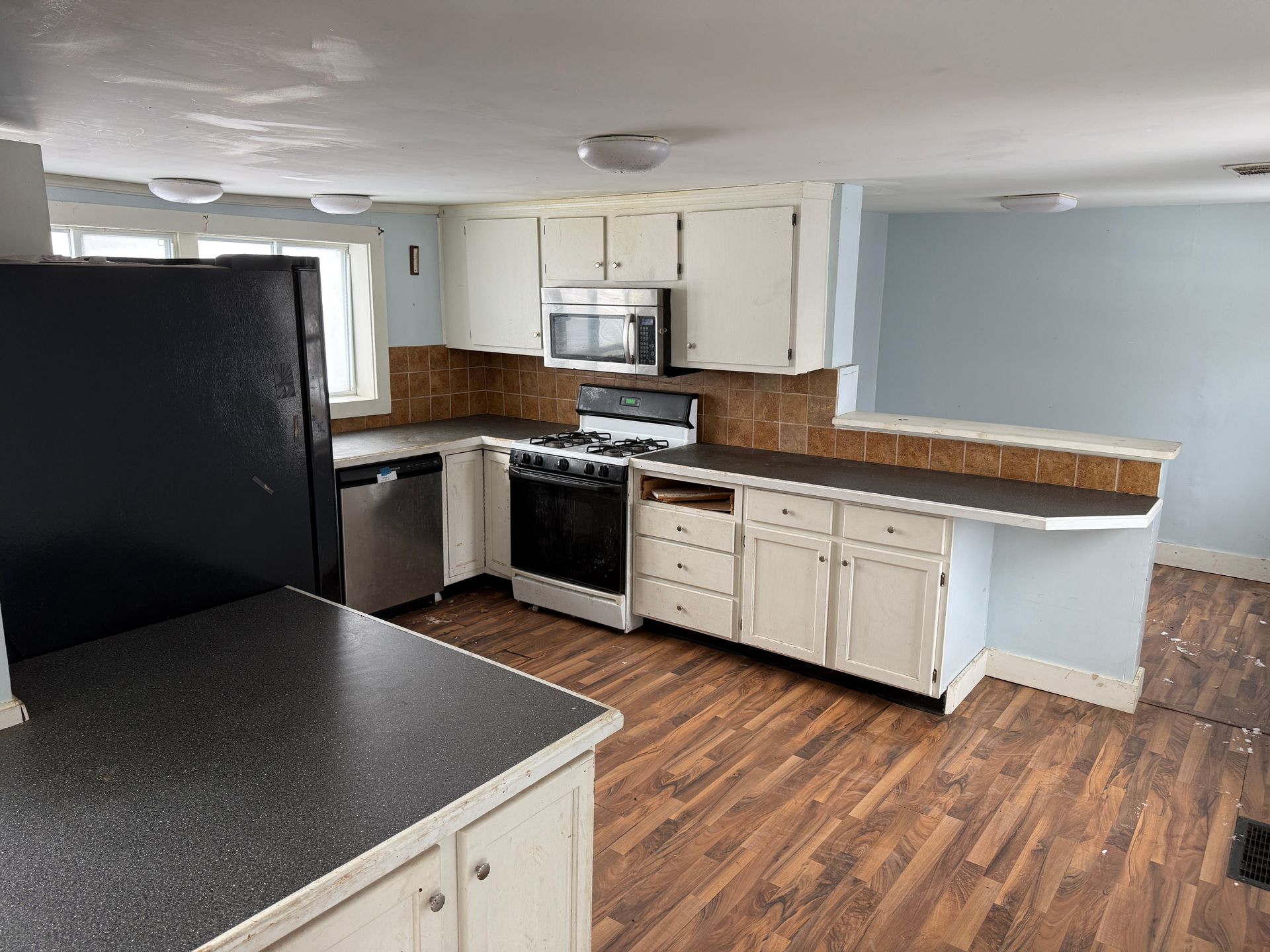 Kitchen with white cabinets, dark appliances, and wood-look flooring.