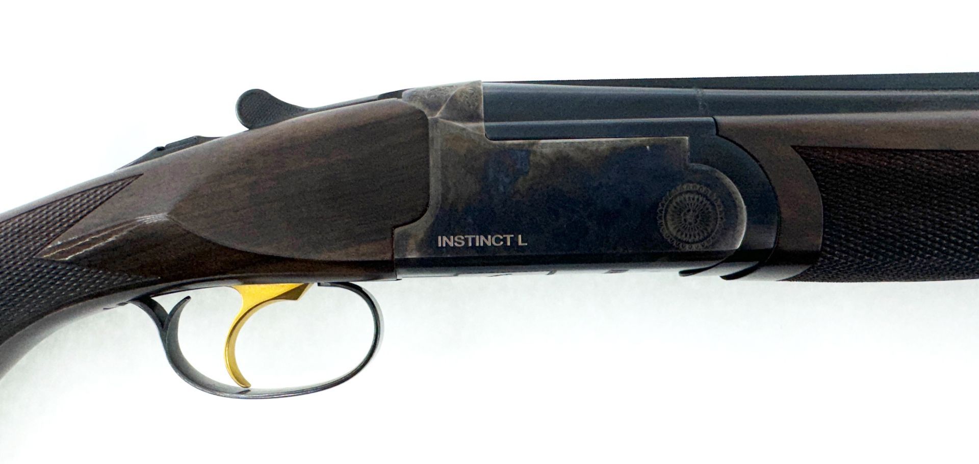 Shotgun with a dark receiver, gold trigger, and checkered grip, on a white background.