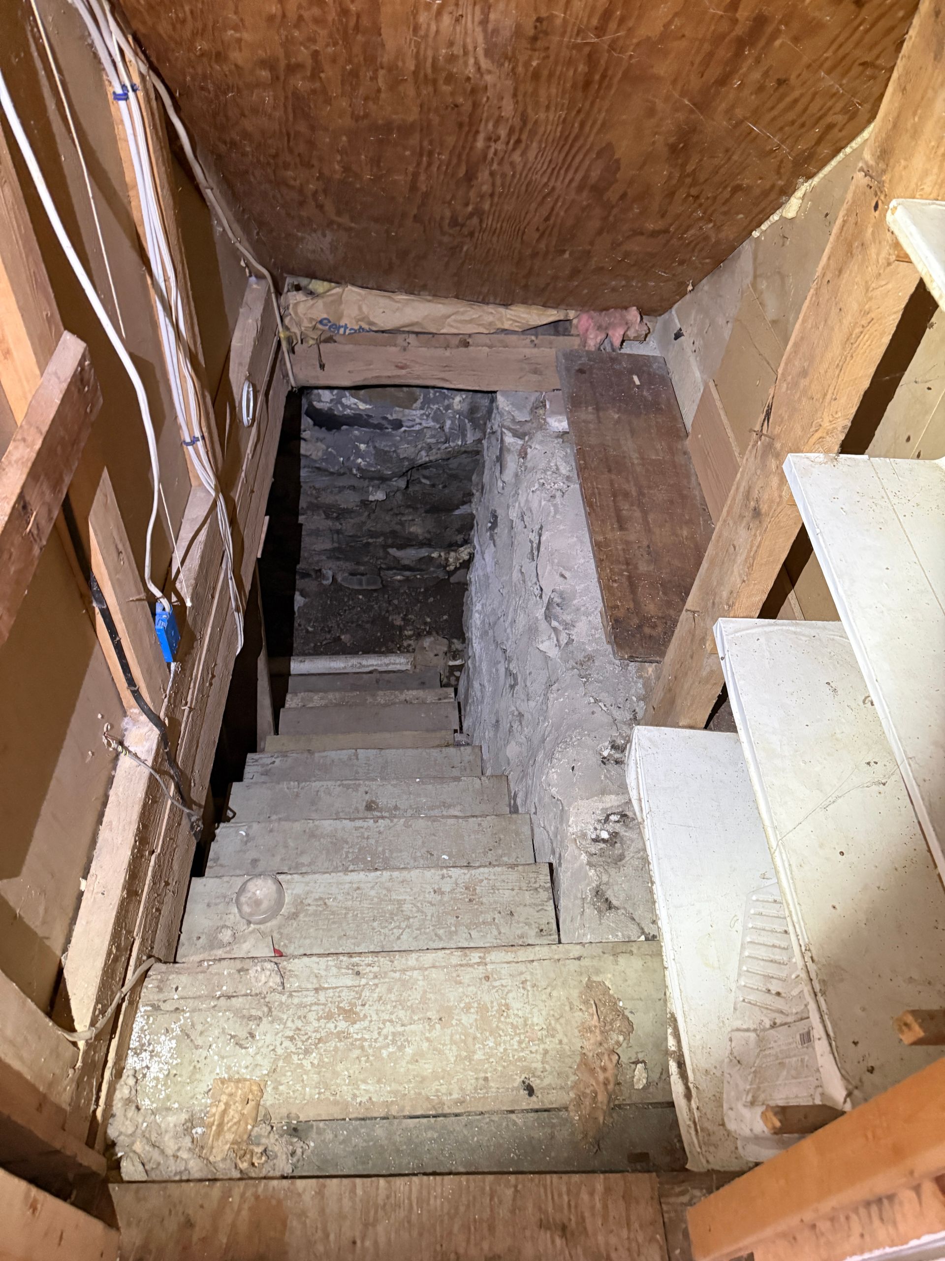 Stairs leading down into a basement area with stone walls. Wooden framing and steps.