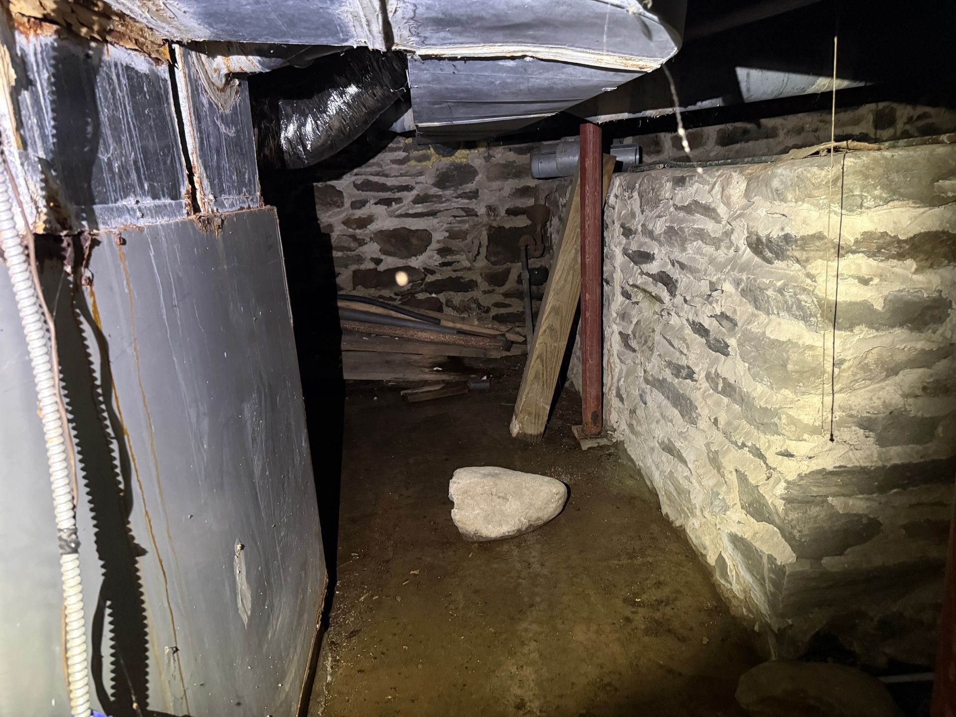 Basement with stone walls, and a large metal box on the left.