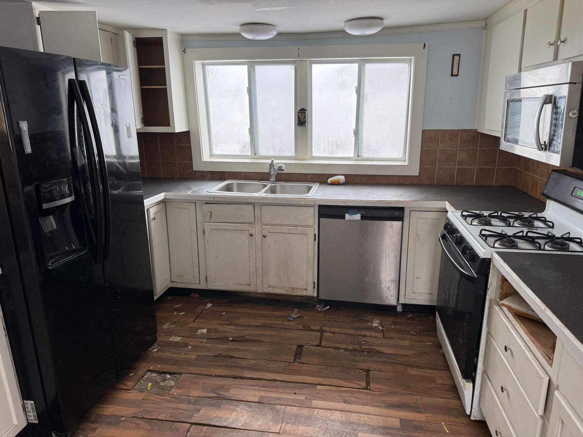 Kitchen with black appliances, white cabinets, and a window above the sink.