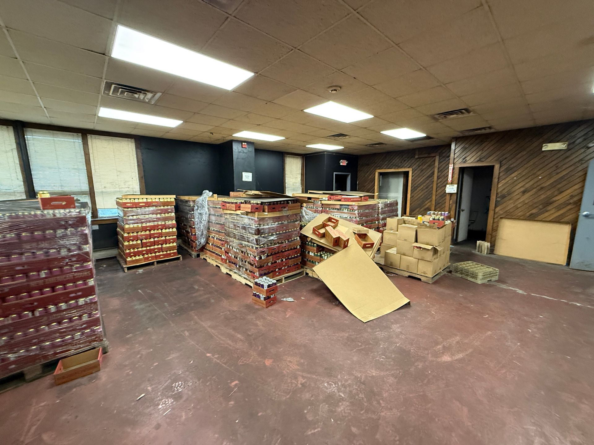 Warehouse interior with pallets of packaged goods and cardboard boxes.
