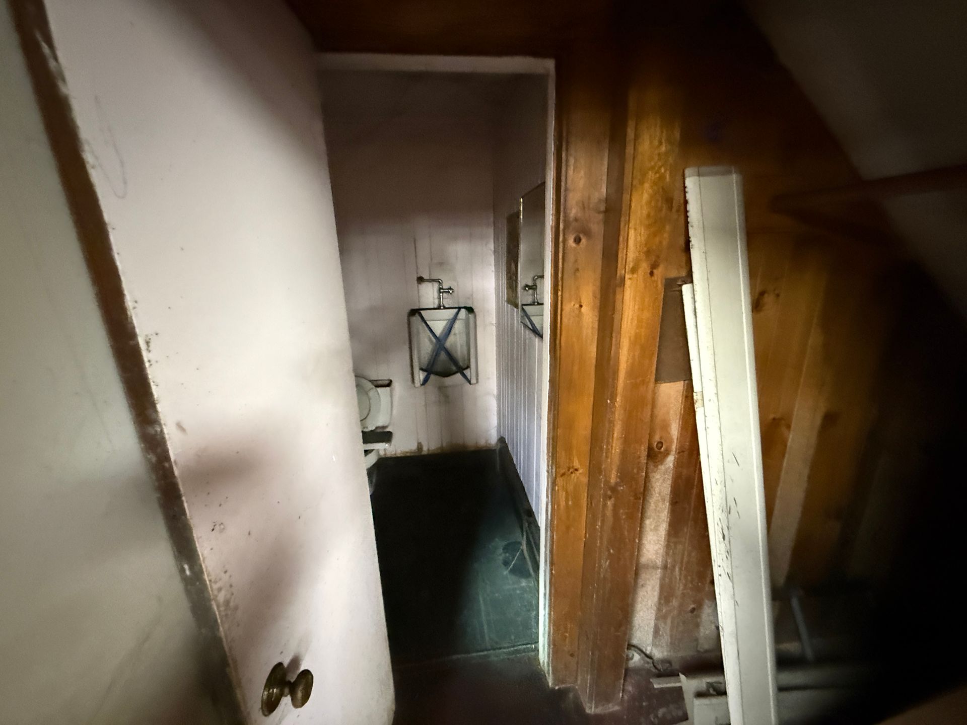 Narrow hallway with open door, pink wall, wooden paneling, and utility.