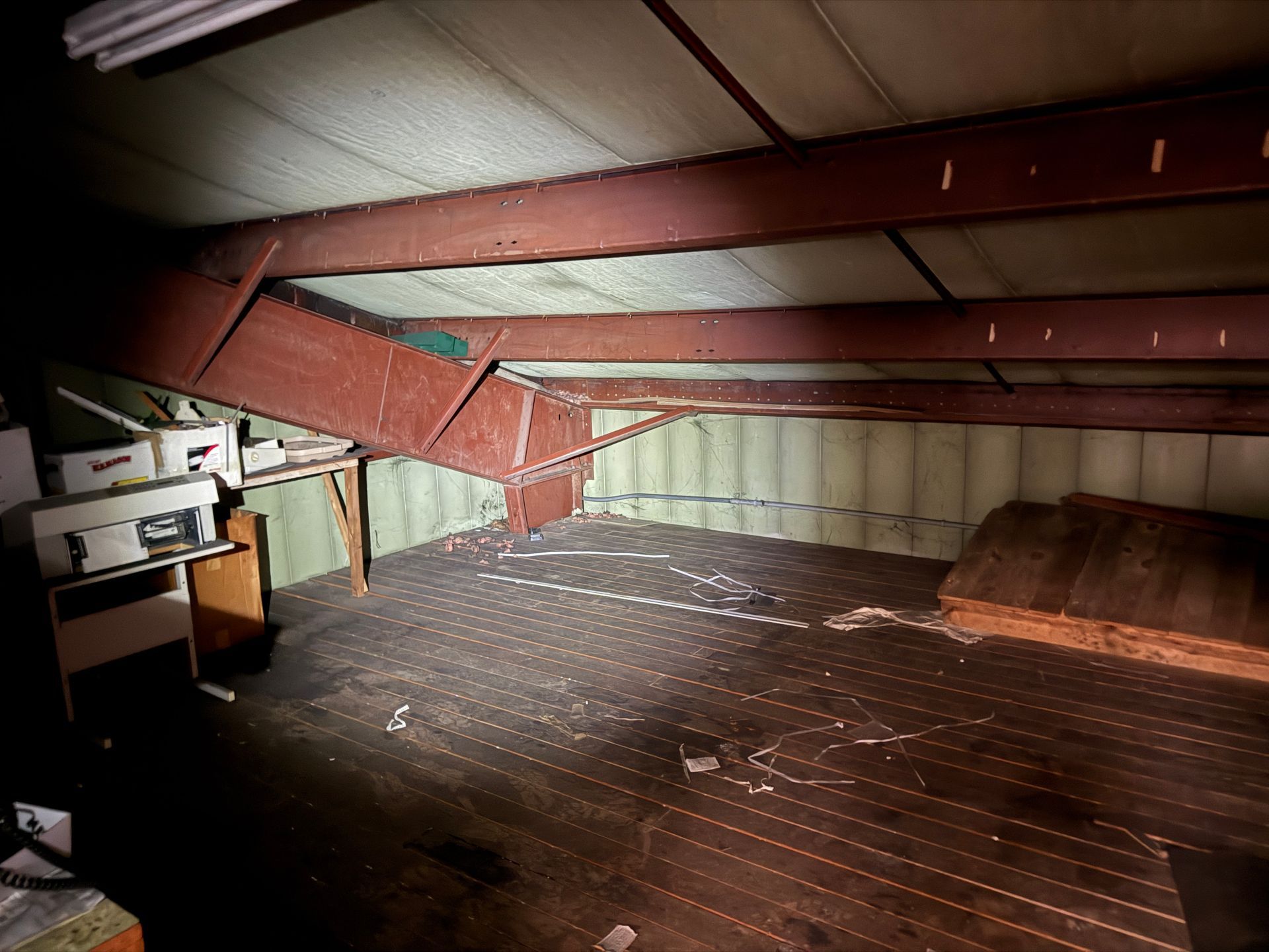 Interior of a room with exposed beams and a dark wooden floor.