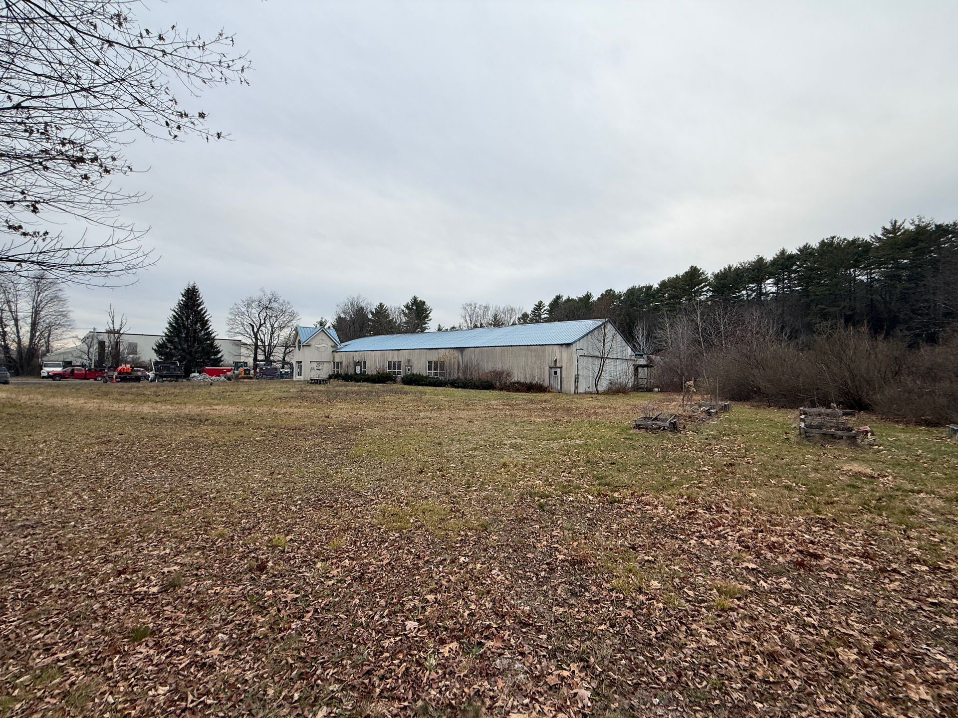 Warhouse and surrounding field on a cloudy day; trees in the background.