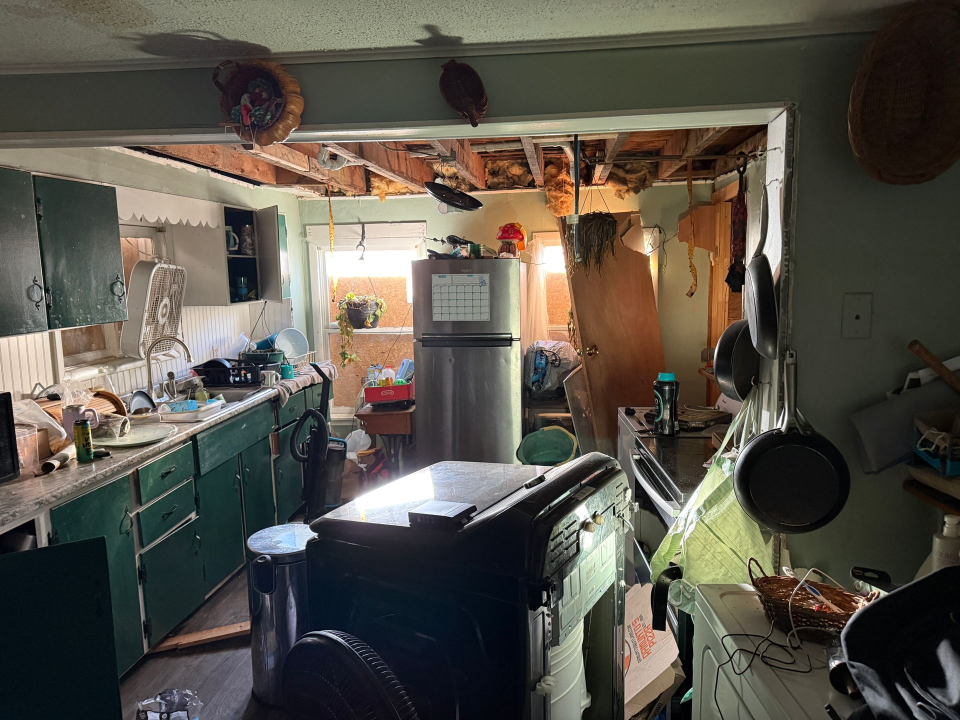 Kitchen with exposed ceiling, green cabinets, appliances.
