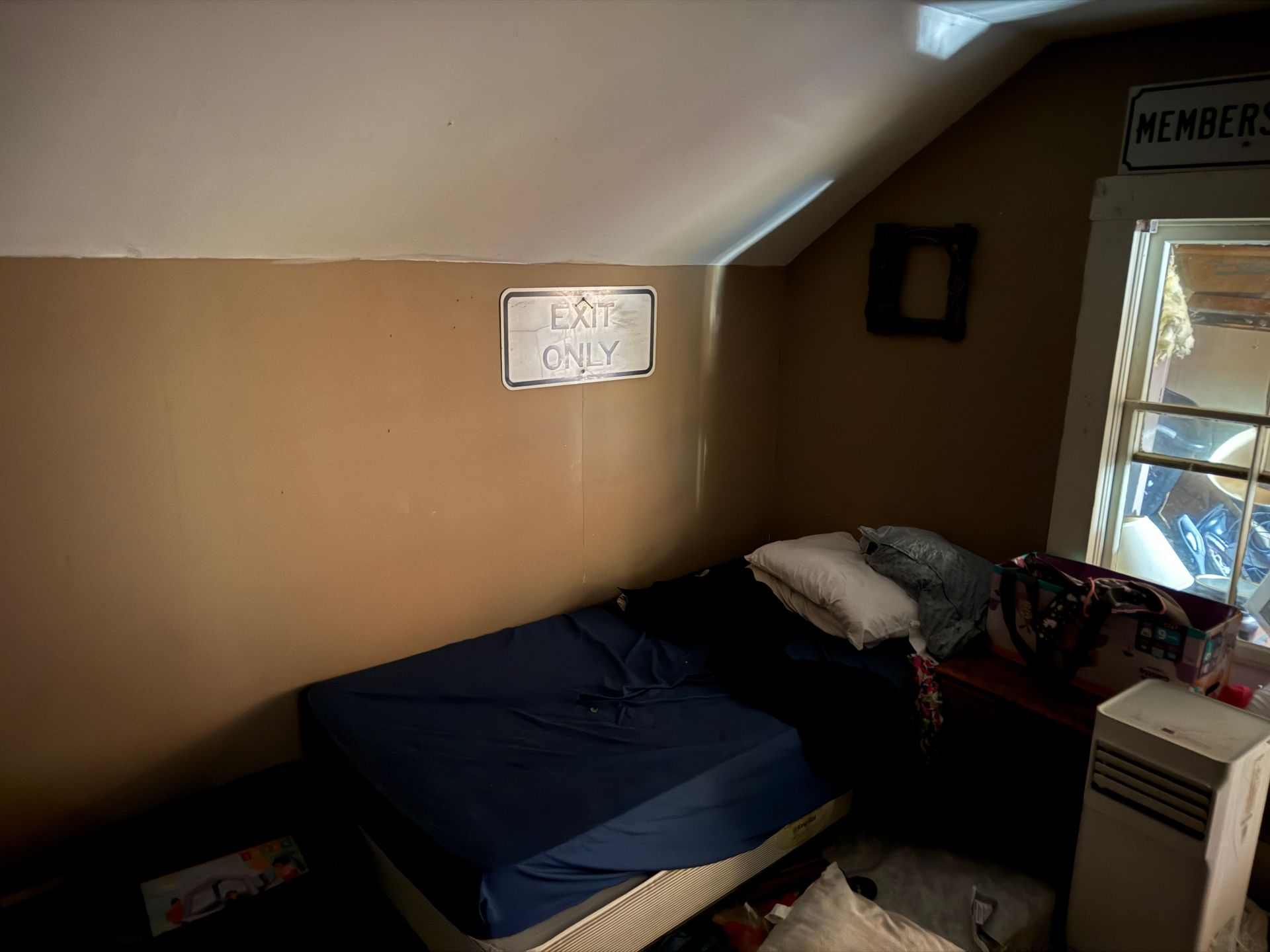 Small bedroom with bed, sign saying 