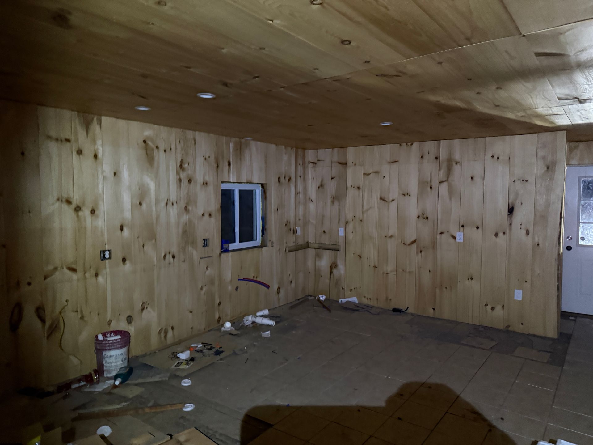 Interior of a room with wood walls and ceiling, a small window.