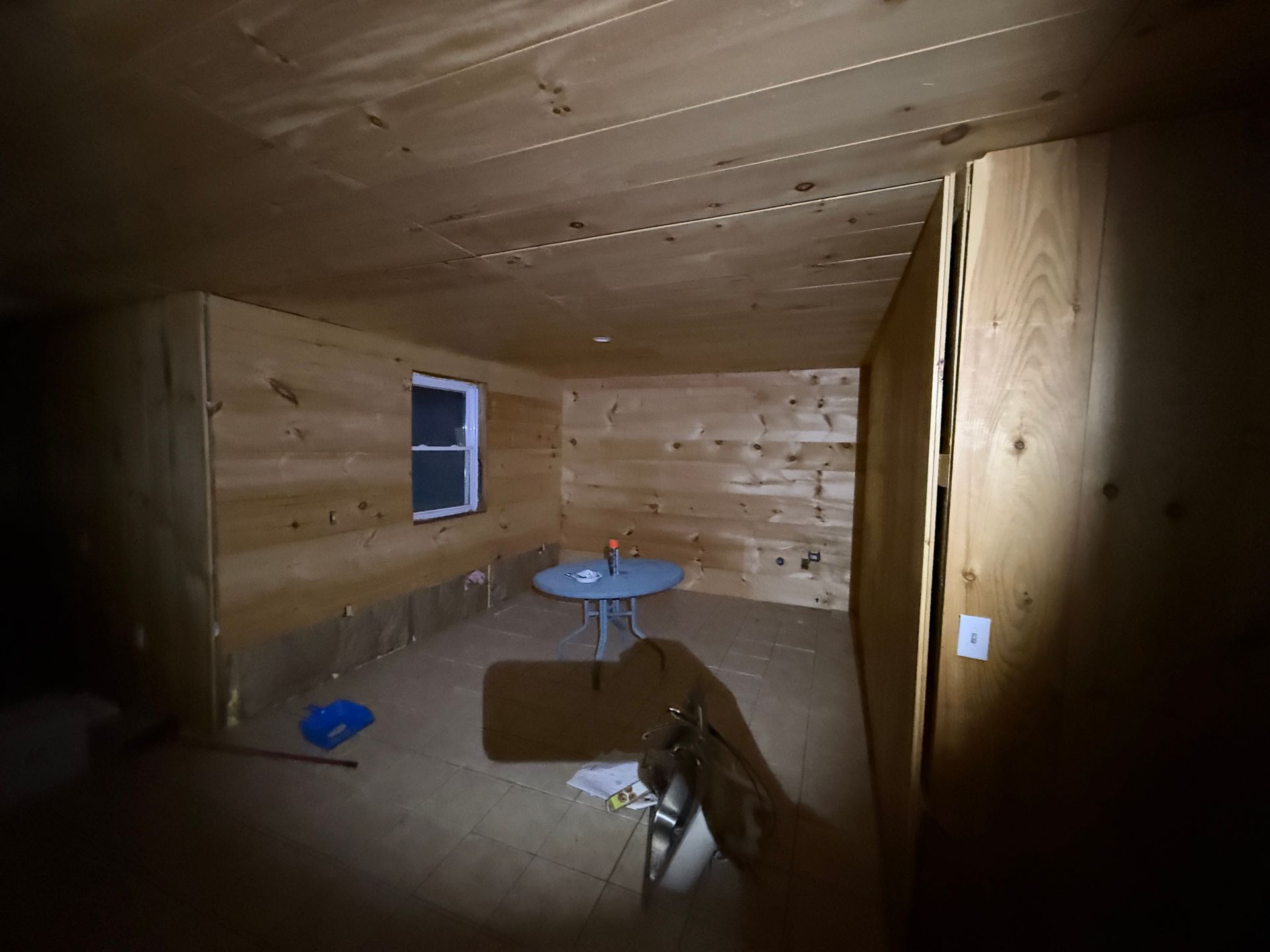 Interior room with wood paneling, a small round table, and a window.