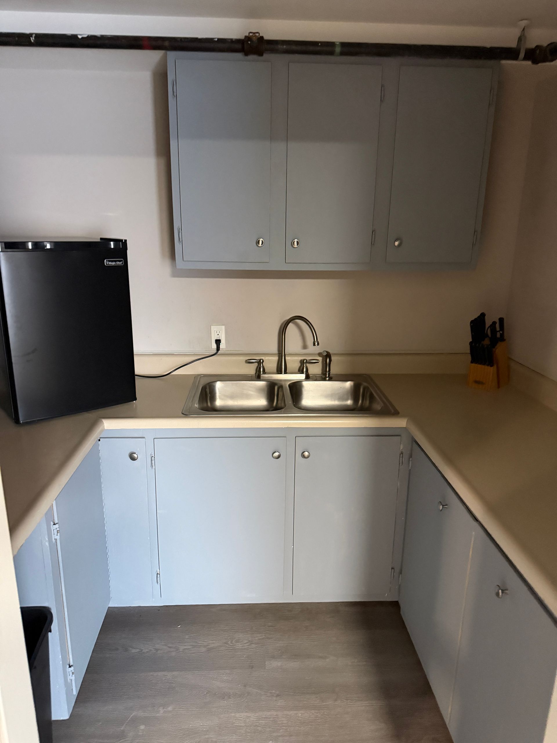 Small kitchen with blue cabinets, a sink, and a mini-fridge.