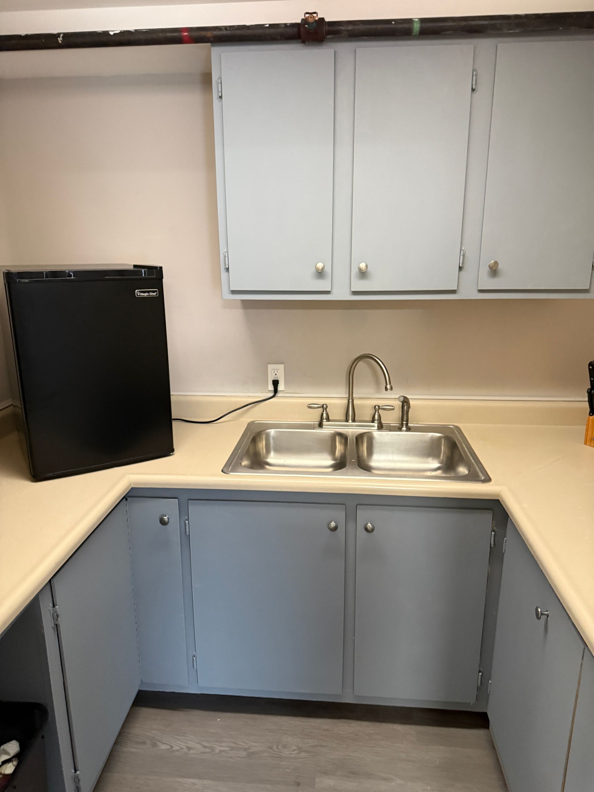 Small kitchen with blue cabinets, a sink, and a black mini-fridge.