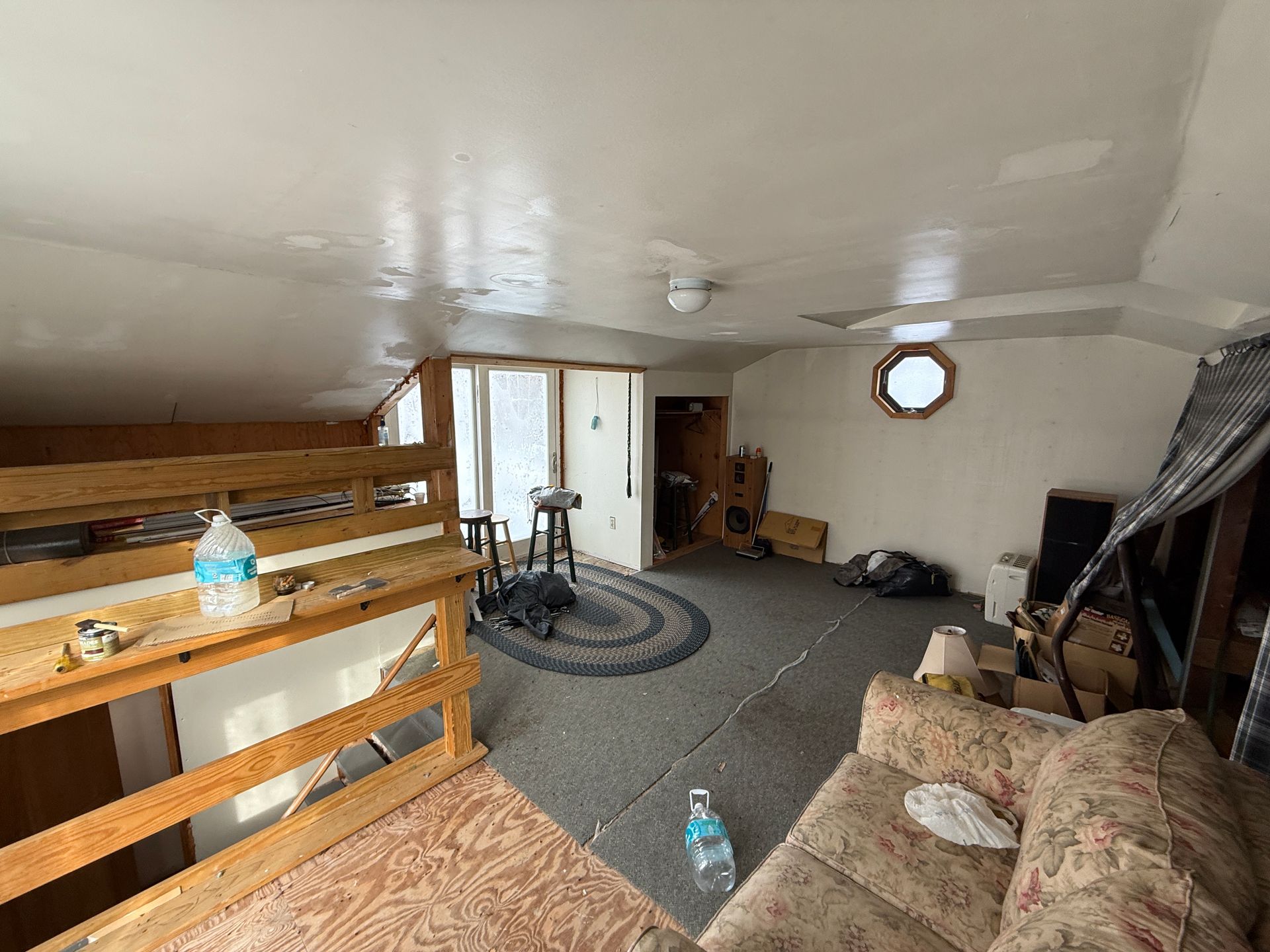 Interior of a room with a loft, showing a couch, rug, and window.
