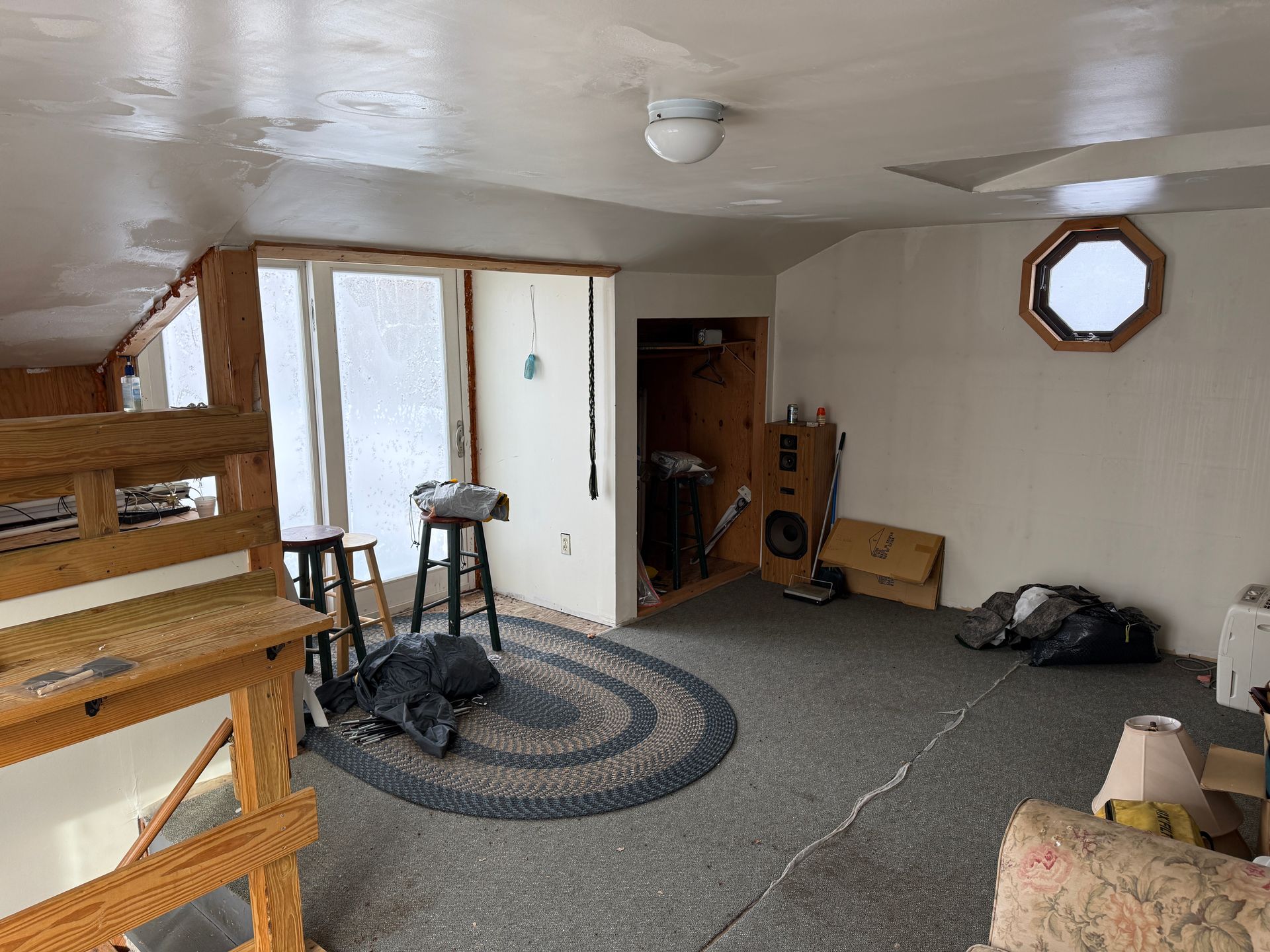 Interior room with carpet, a bunk bed, and a circular rug. There is a closet, windows and a ceiling light.