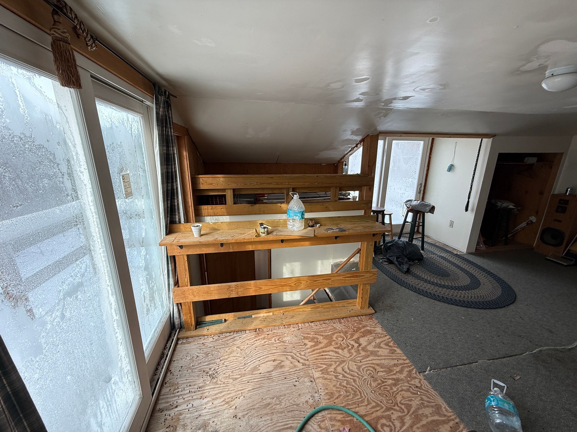 Wooden workbench in a room with sliding glass doors, a raised platform, and an oval rug.