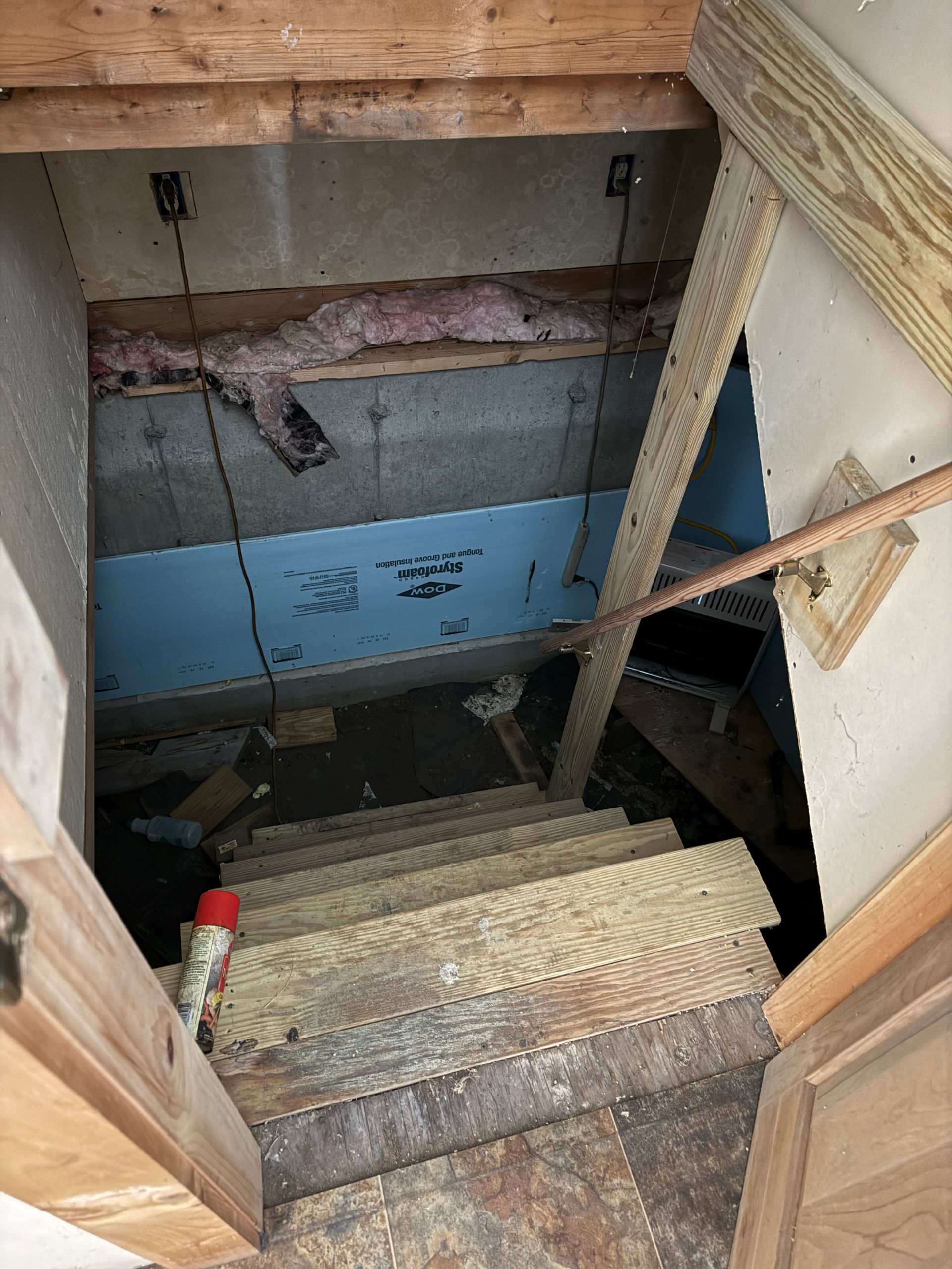 Staircase descending into a basement. Wooden steps and support beams.