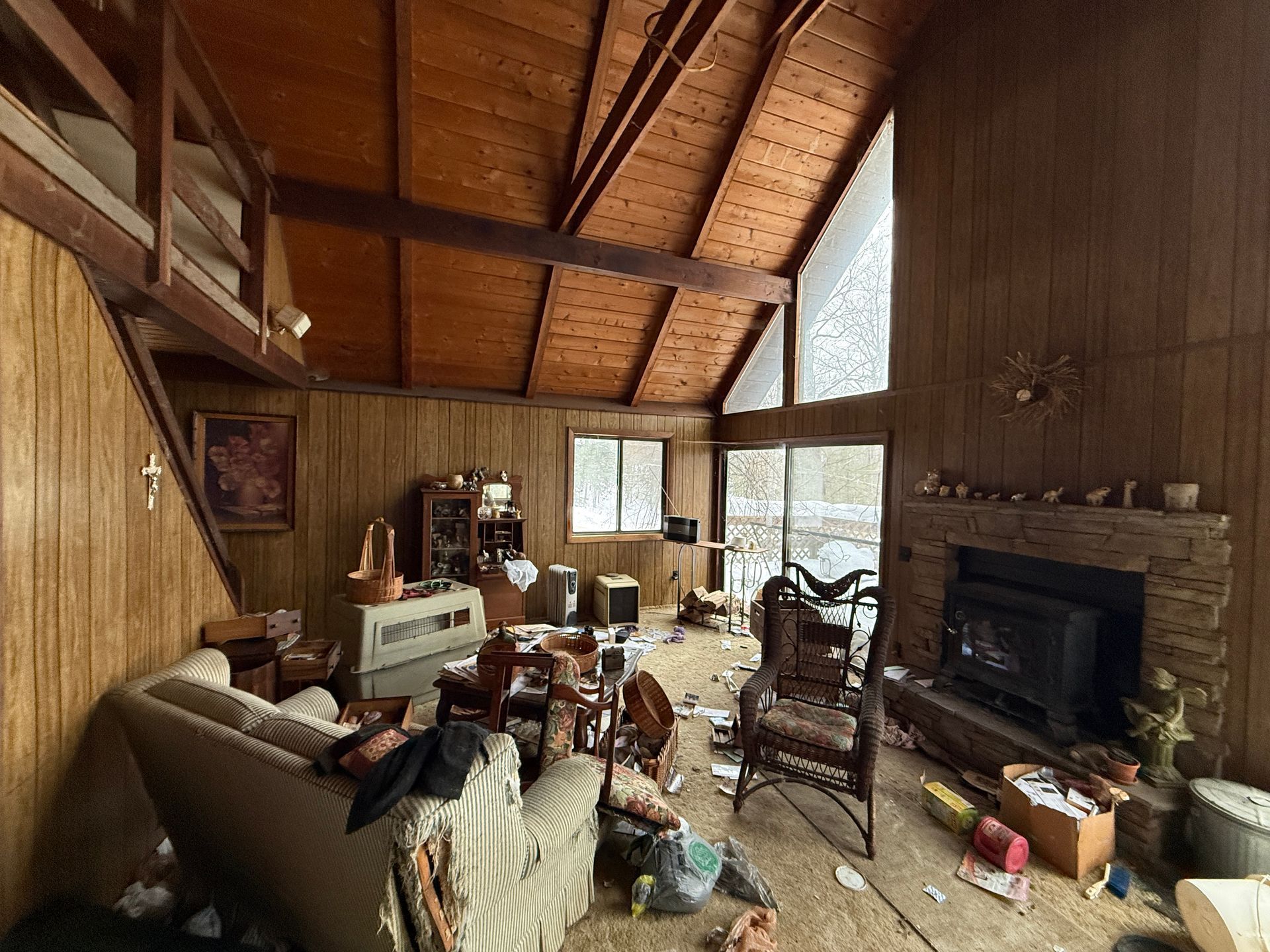 Interior of a cabin-like space with wood paneling, fireplace, and loft.