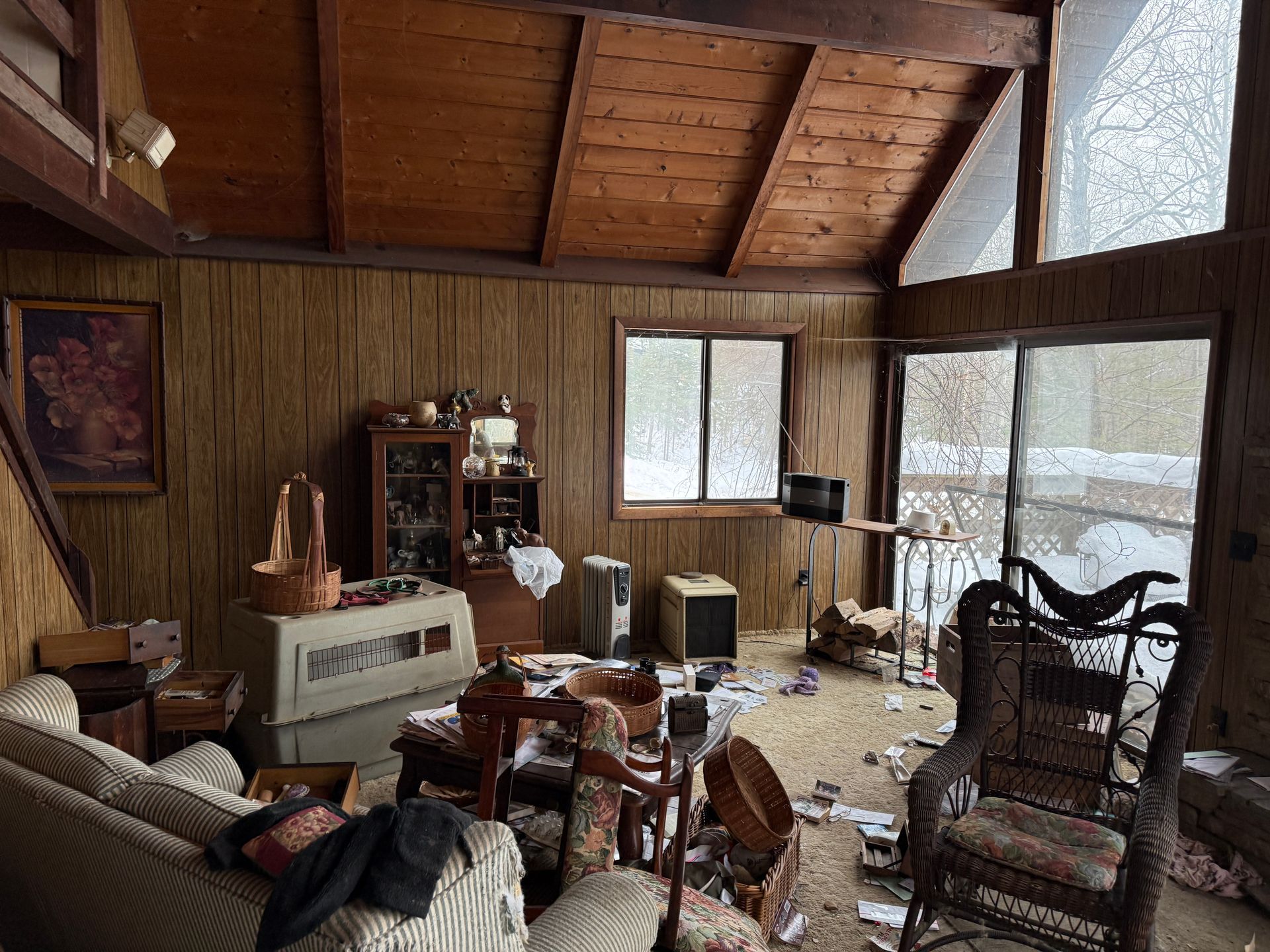 Living room with wooden paneling, furniture, and a window overlooking a snowy scene.