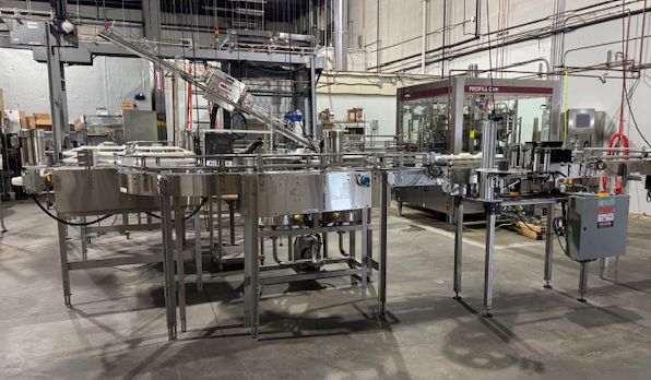 Industrial bottling line with stainless steel machinery in a factory setting.