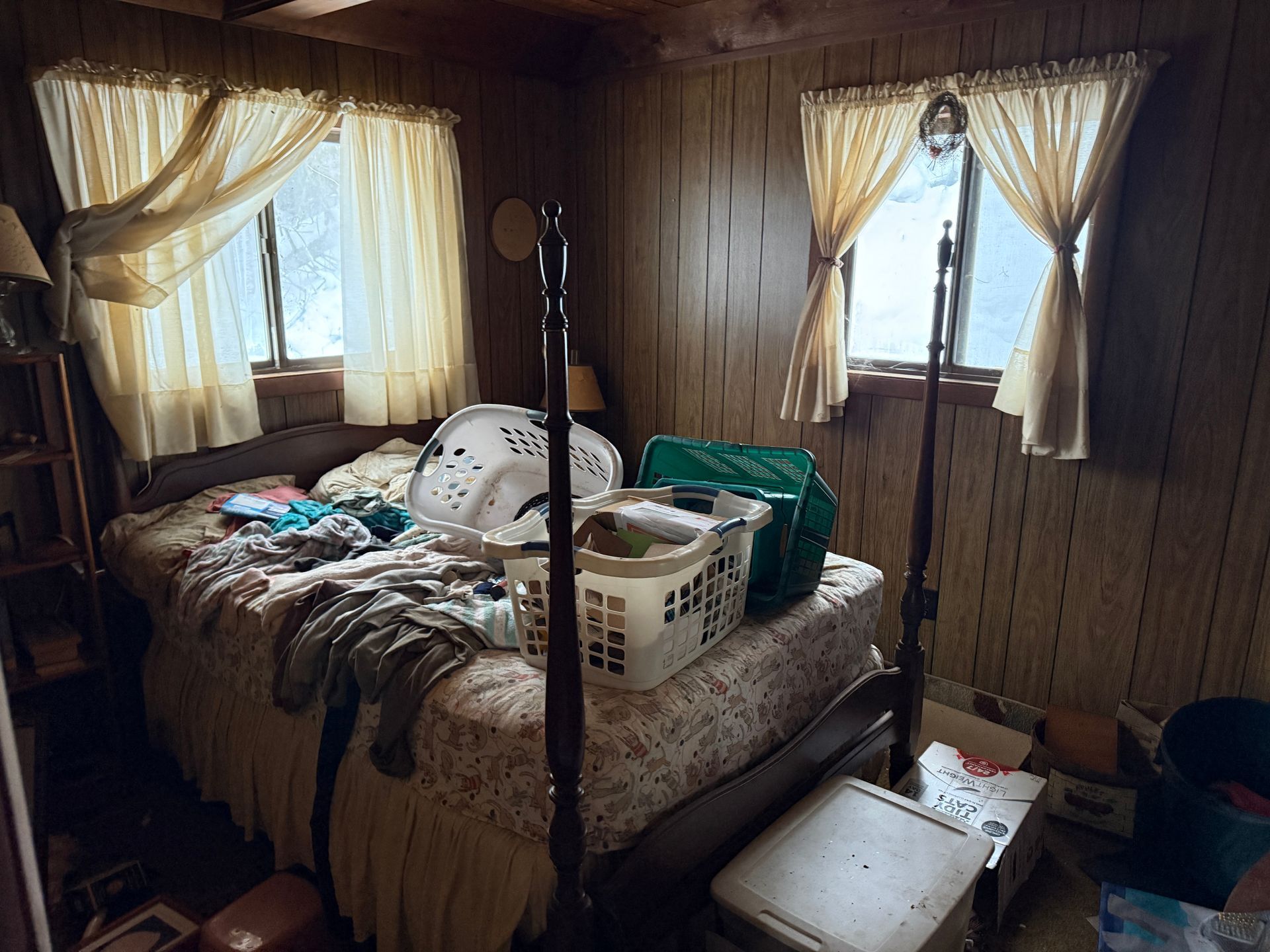 Bedroom with bed, two windows with curtains.