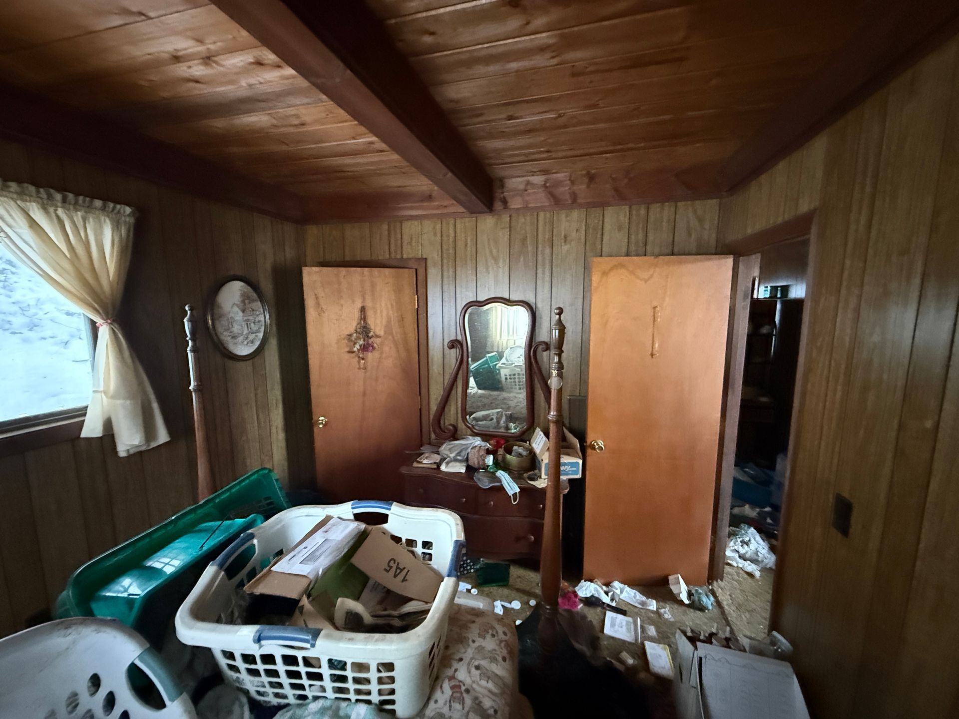 Bedroom: wood paneling, dresser with mirror, two doors, a window.
