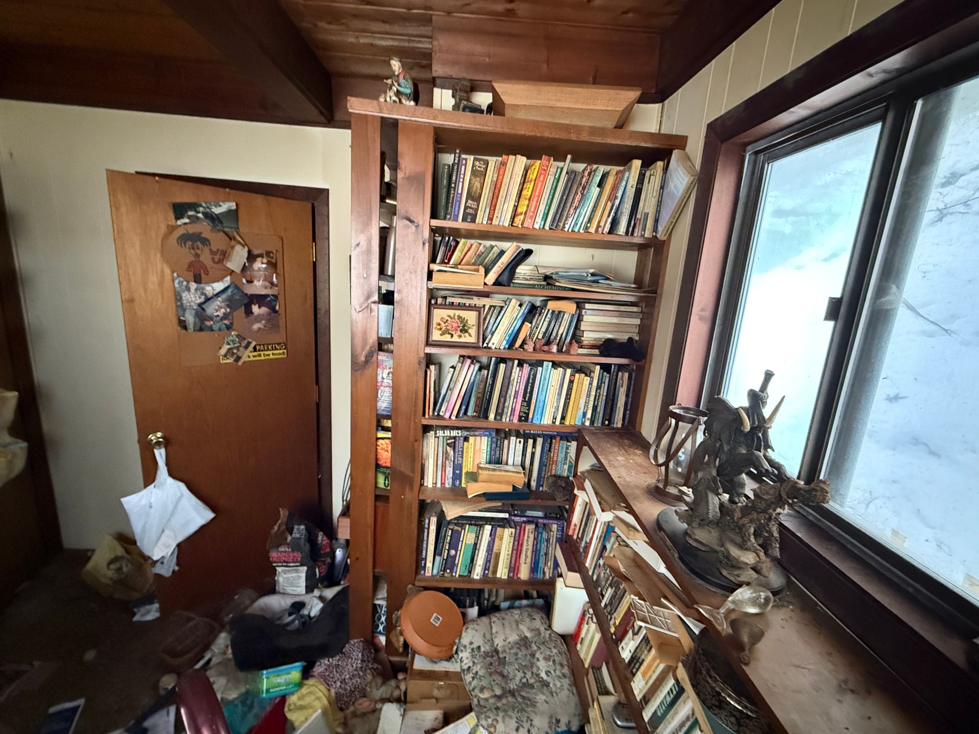 Bookshelves in a corner near a window. Books are colorful and stacked.