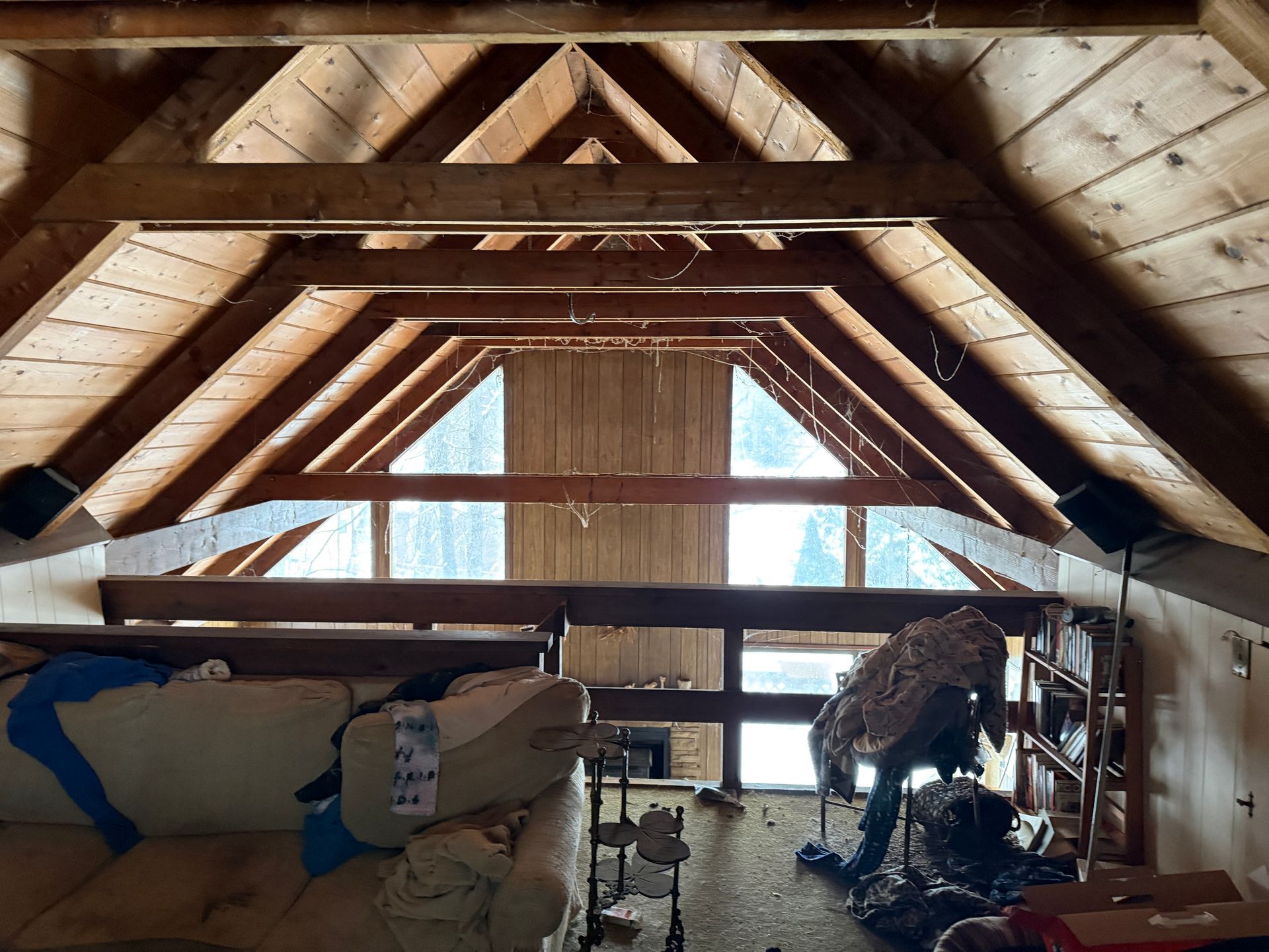Interior view of an attic with exposed wooden beams, natural light.