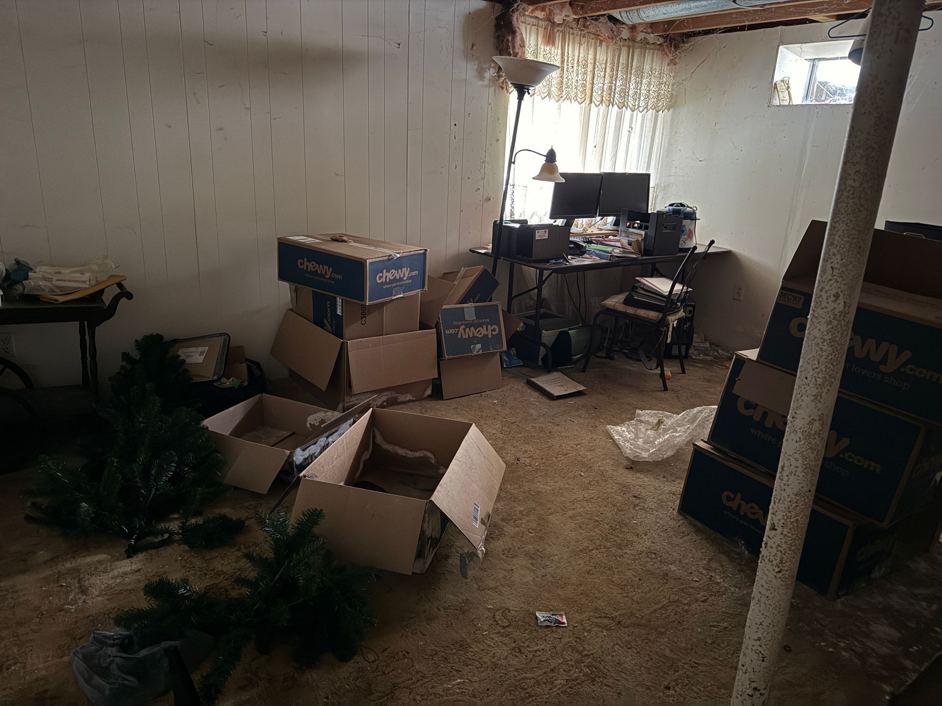 Basement room with open boxes, desk.