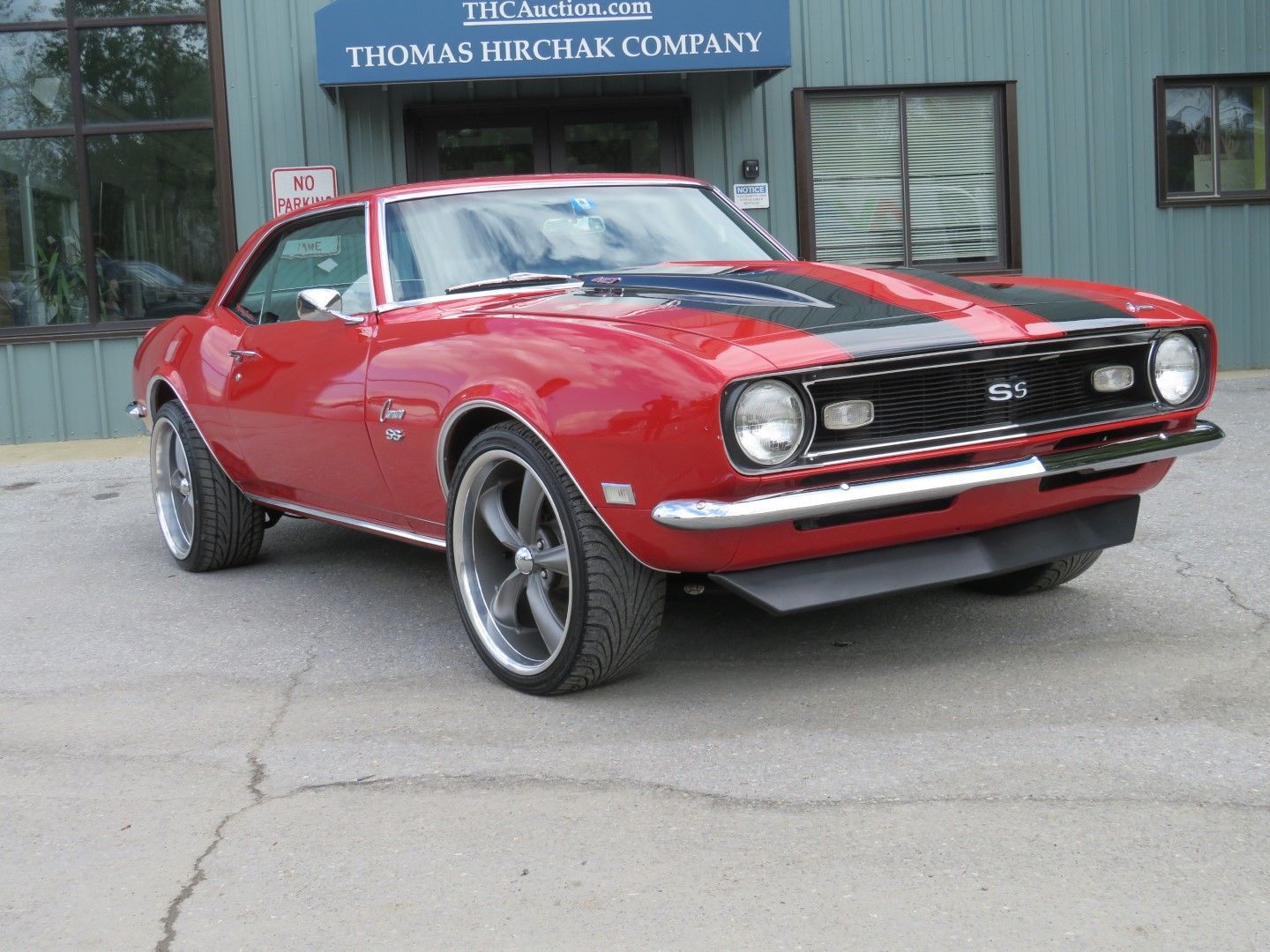Red 1967 Chevrolet Camaro SS with black stripes, parked in front of a building.