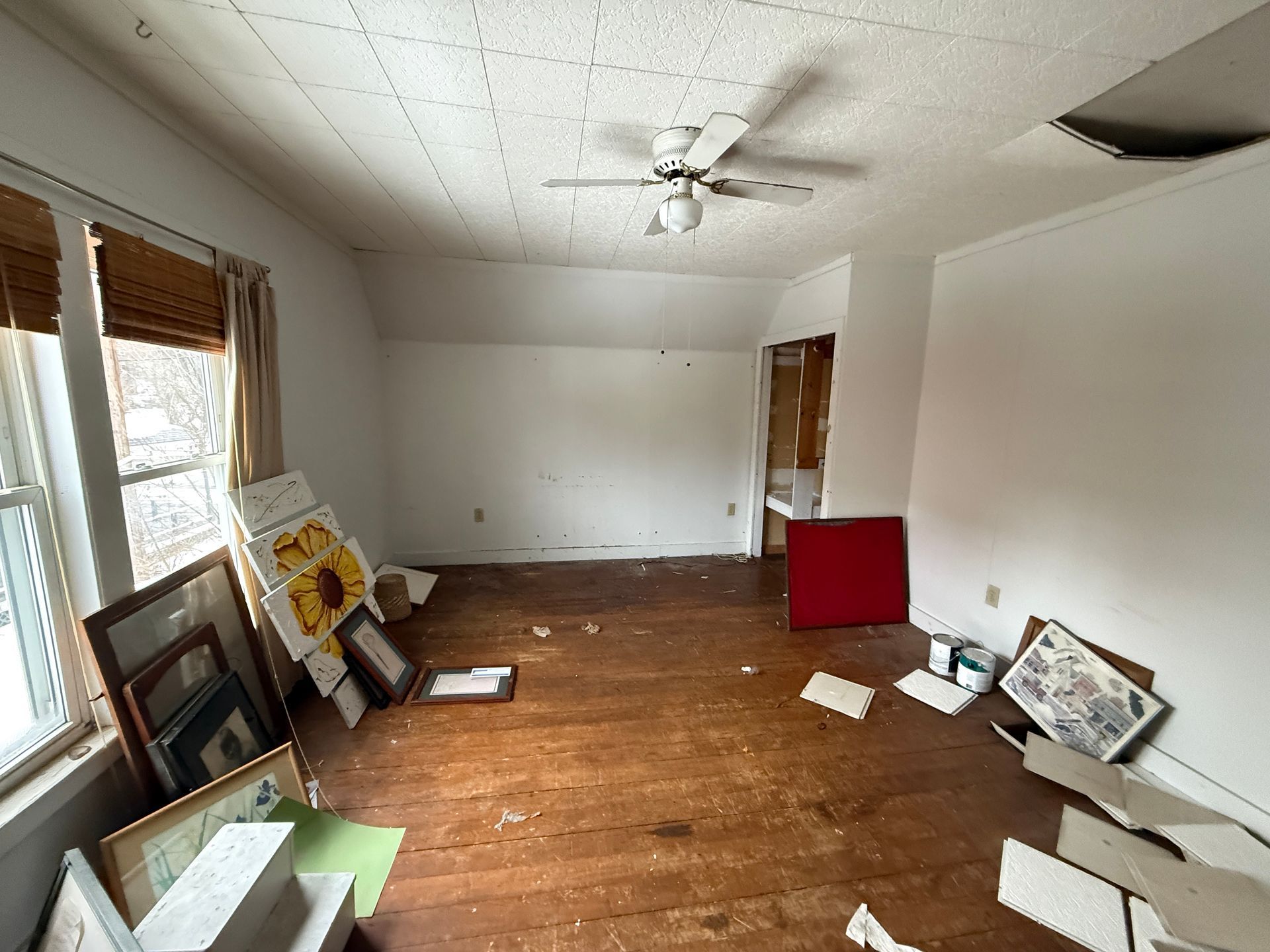 An empty room with wood floors, white walls, a ceiling fan.