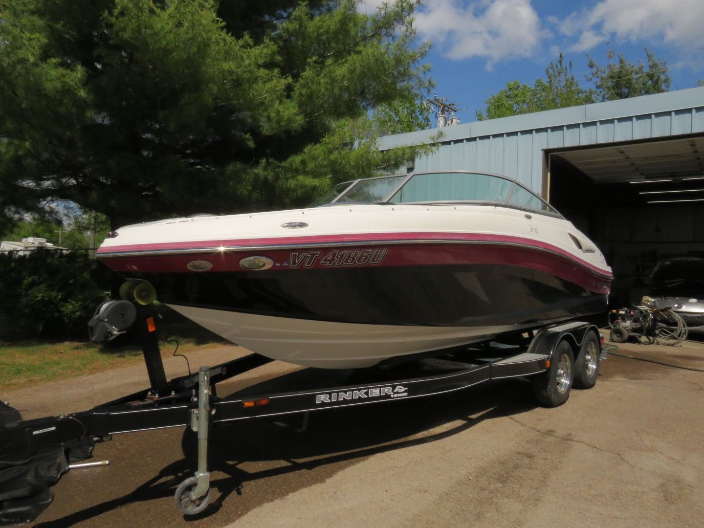 A black and white boat with red trim sits on a trailer in front of a building.